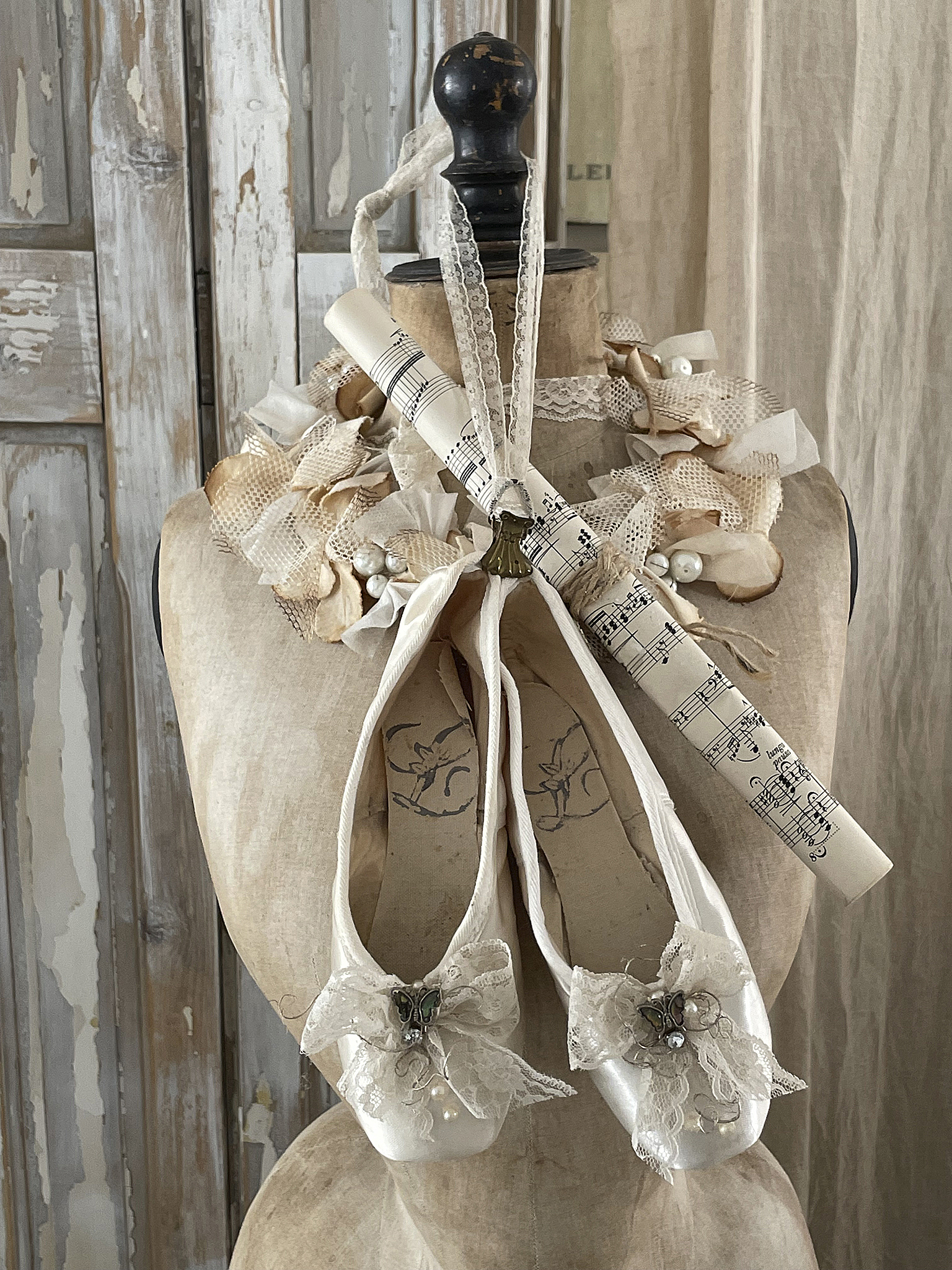 Elegante Ballettschuhe mit Dekoration und Notenrolle Zwei elegante Ballettschuhe mit Spitze und einem Schmuckdetail, dekoriert mit einer Notenrolle und Blumenarrangement