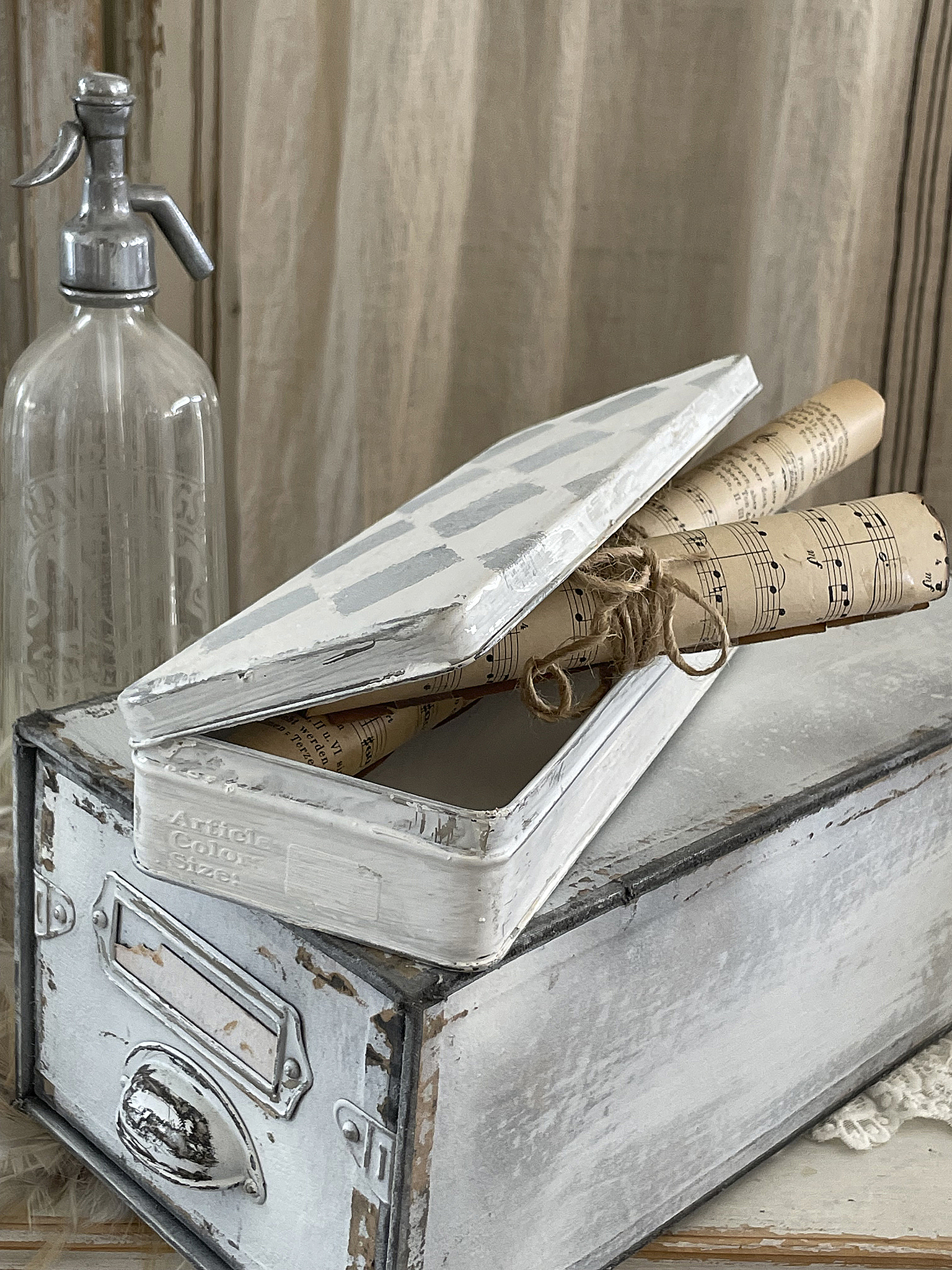 Aufbewahrungsbox mit geöffneter Oberseite, darin alte Notenrollen, daneben eine Glasflasche