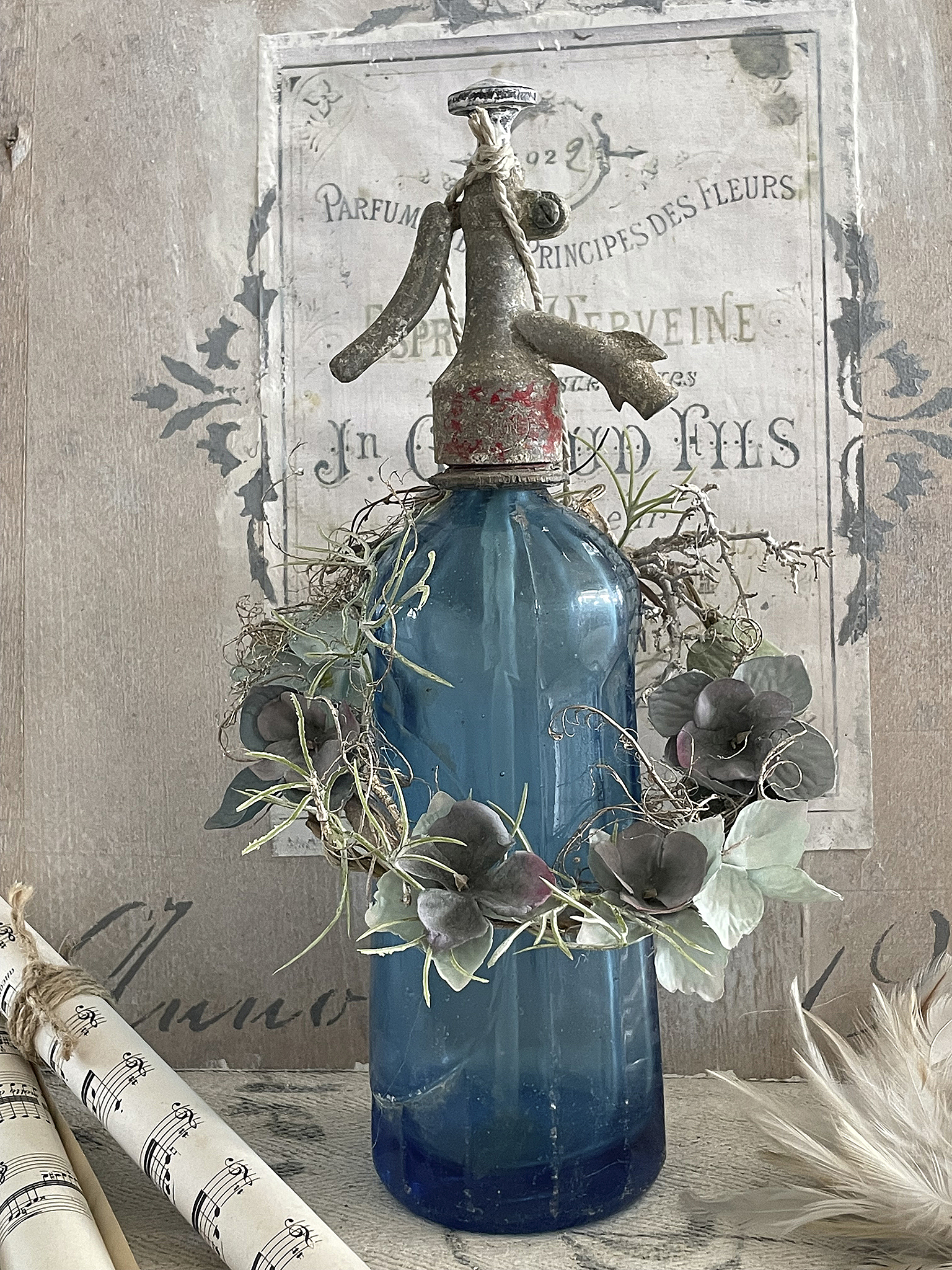 Dekorative blaue Flasche mit einem Wasserzerstäuber und floralen Elementen
