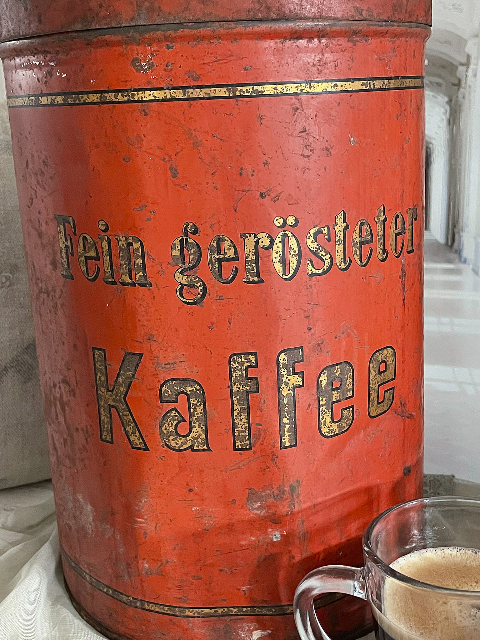 Rote Dose mit der Aufschrift 'Fein gerösteter Kaffee' und einer Tasse Kaffee