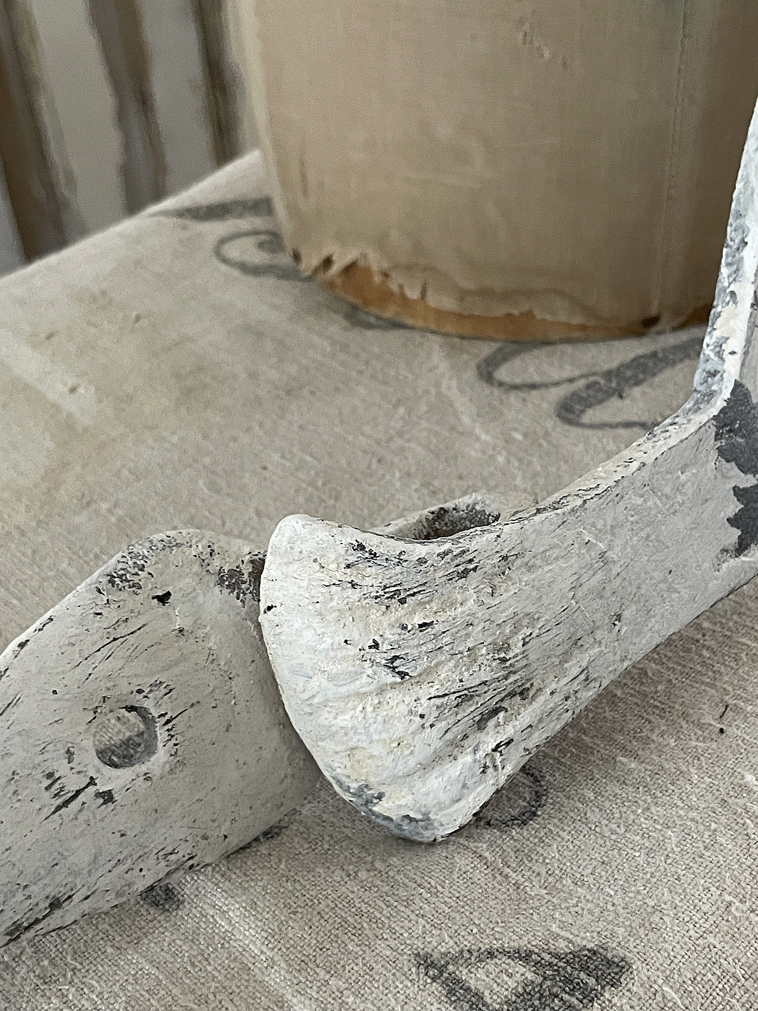Detailaufnahme eines weißen, abgenutzten Holzgegenstandes auf einem Tisch. Nahaufnahme eines weißen, abgenutzten Holzteils auf einer Tischoberfläche.
