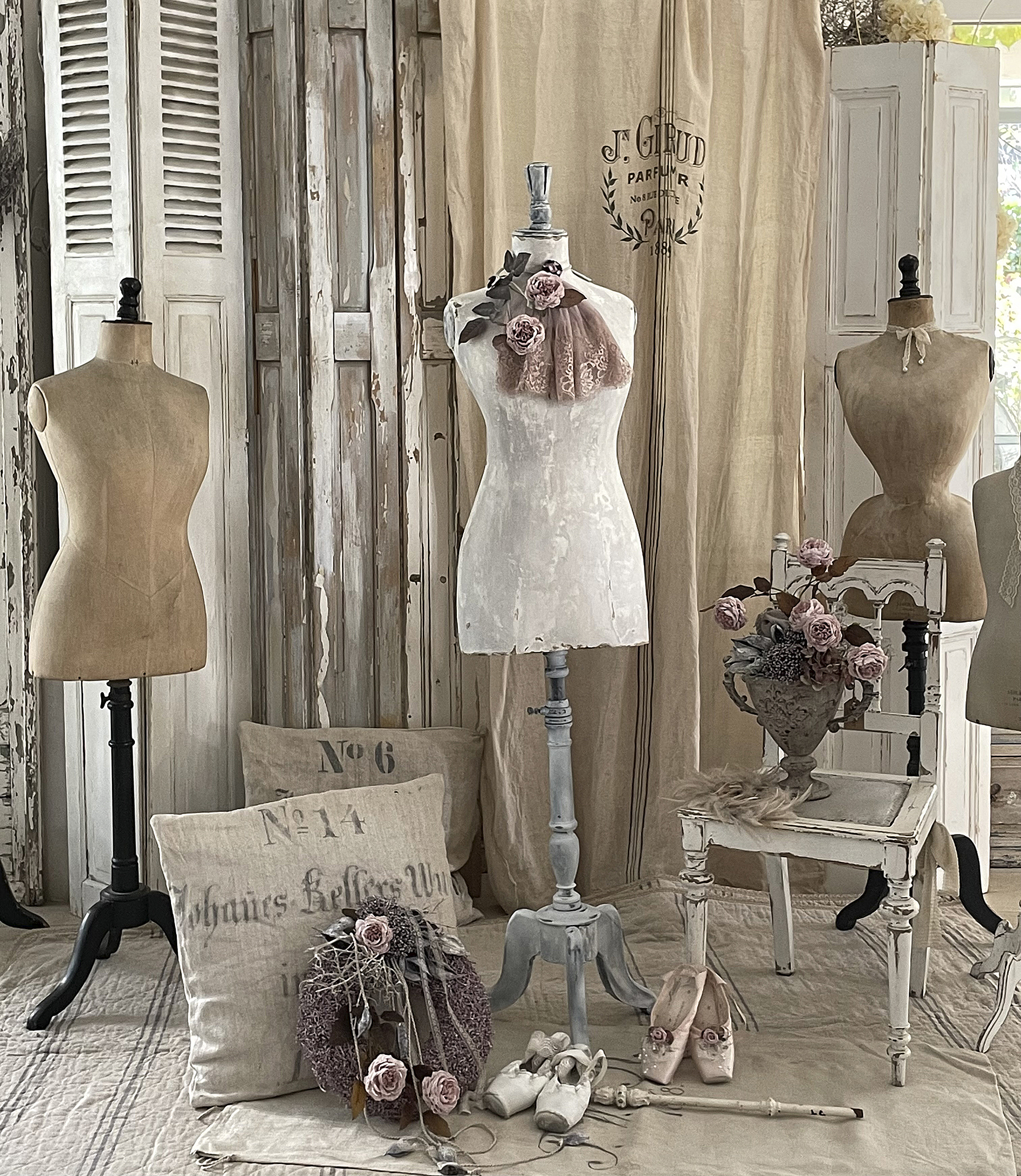 Elegante Schaufensterdekoration mit Schneiderpuppen und Vintage-Accessoires Schaufenster mit mehreren Schneiderpuppen, Vintage-Stuhl, Kissen und Dekorationselementen wie Rosen.