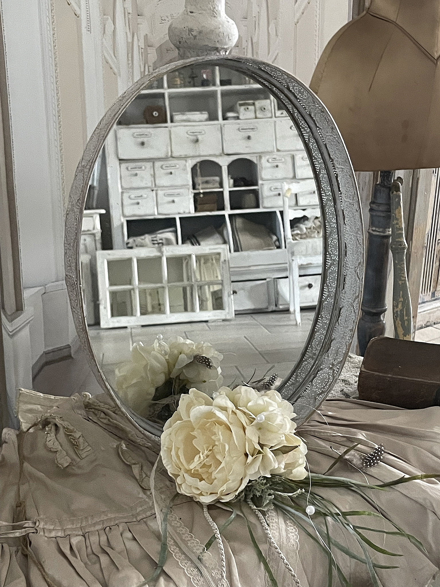 Antiker Spiegel mit floraler Dekoration und vintage Stil Schöner ovaler Spiegel mit weißen Blumen und vintage Einrichtung im Hintergrund