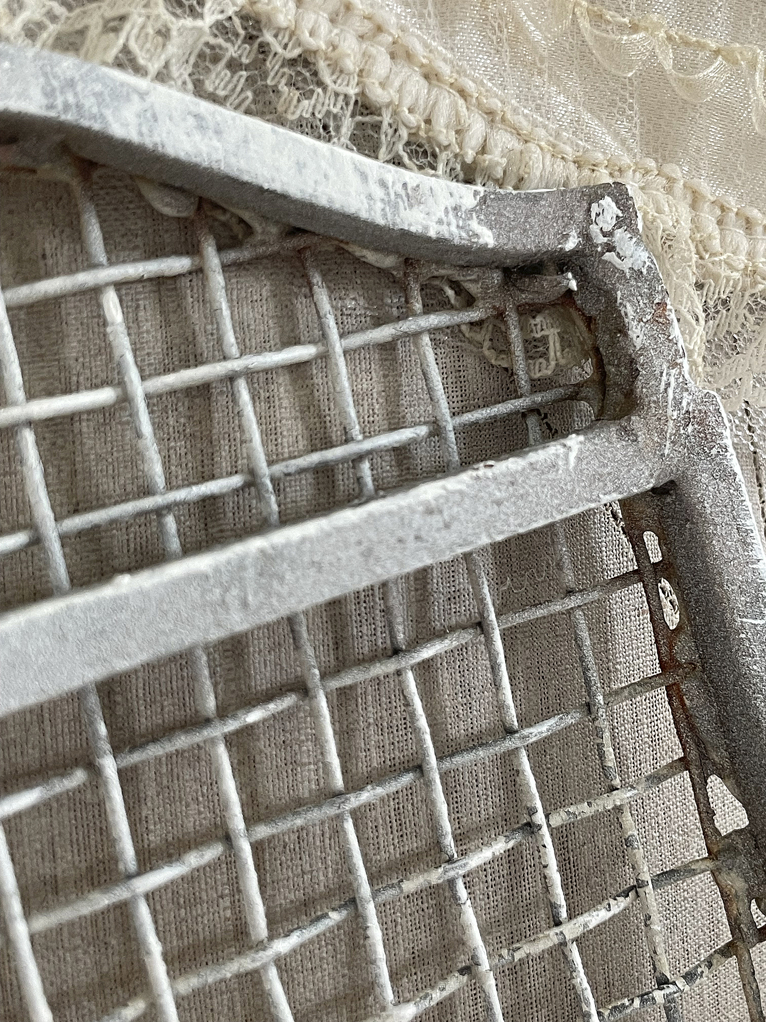 Vintage Gitterstruktur aus Metall für kreative Bastelprojekte Nahaufnahme eines rustikalen Metallgitters auf einem hellen Stoffhintergrund