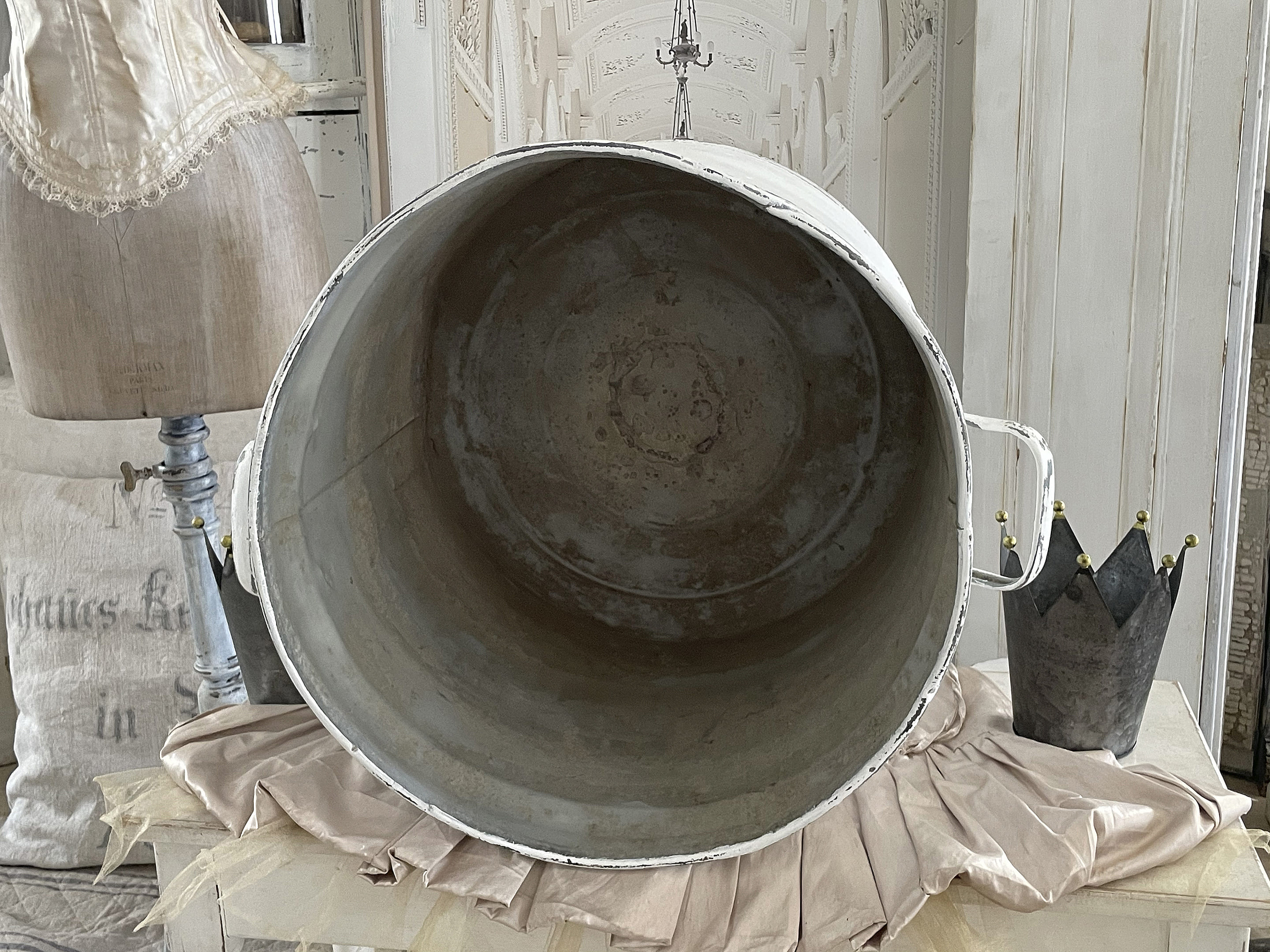 Innenansicht einer großen Metallwanne auf einem Tisch, umgeben von einem historischen Mannequin und einer dekorativen Krone.