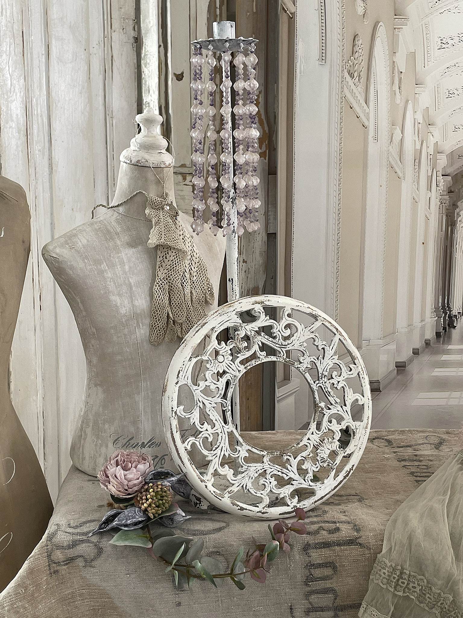 Dekorativer vintage Rahmen mit floralen Motiven und Blütenarrangement Dekorativer weißer Rahmen und modisches Zubehör auf einem Tisch im stilvollen Ambiente