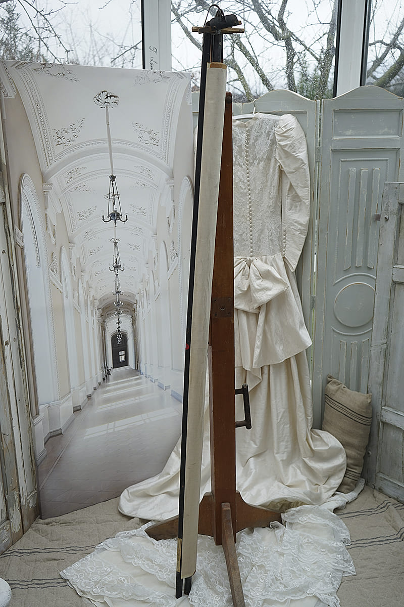 Hochwertiges Hochzeitskleid an einer Holzstaffelei mit dekorativem Hintergrund