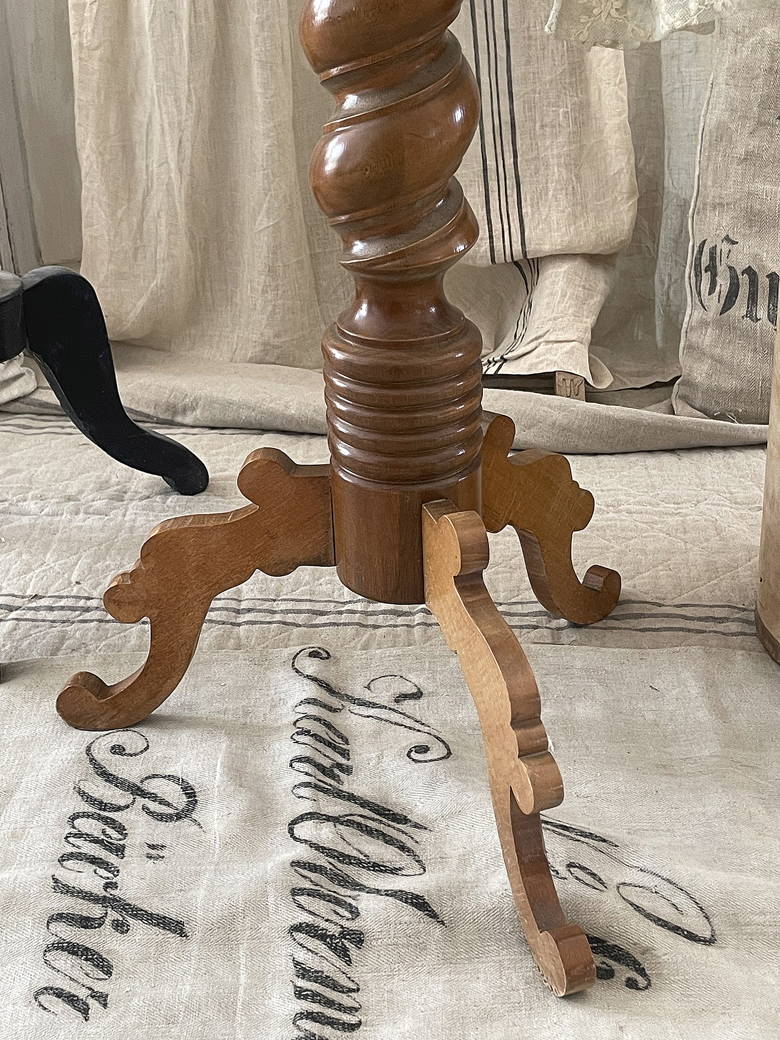Eleganter Tischfuß mit geschwungenen Details aus Holz Nahaufnahme eines geschwungenen Tischfußes aus Holz auf einem antiken Bezug.