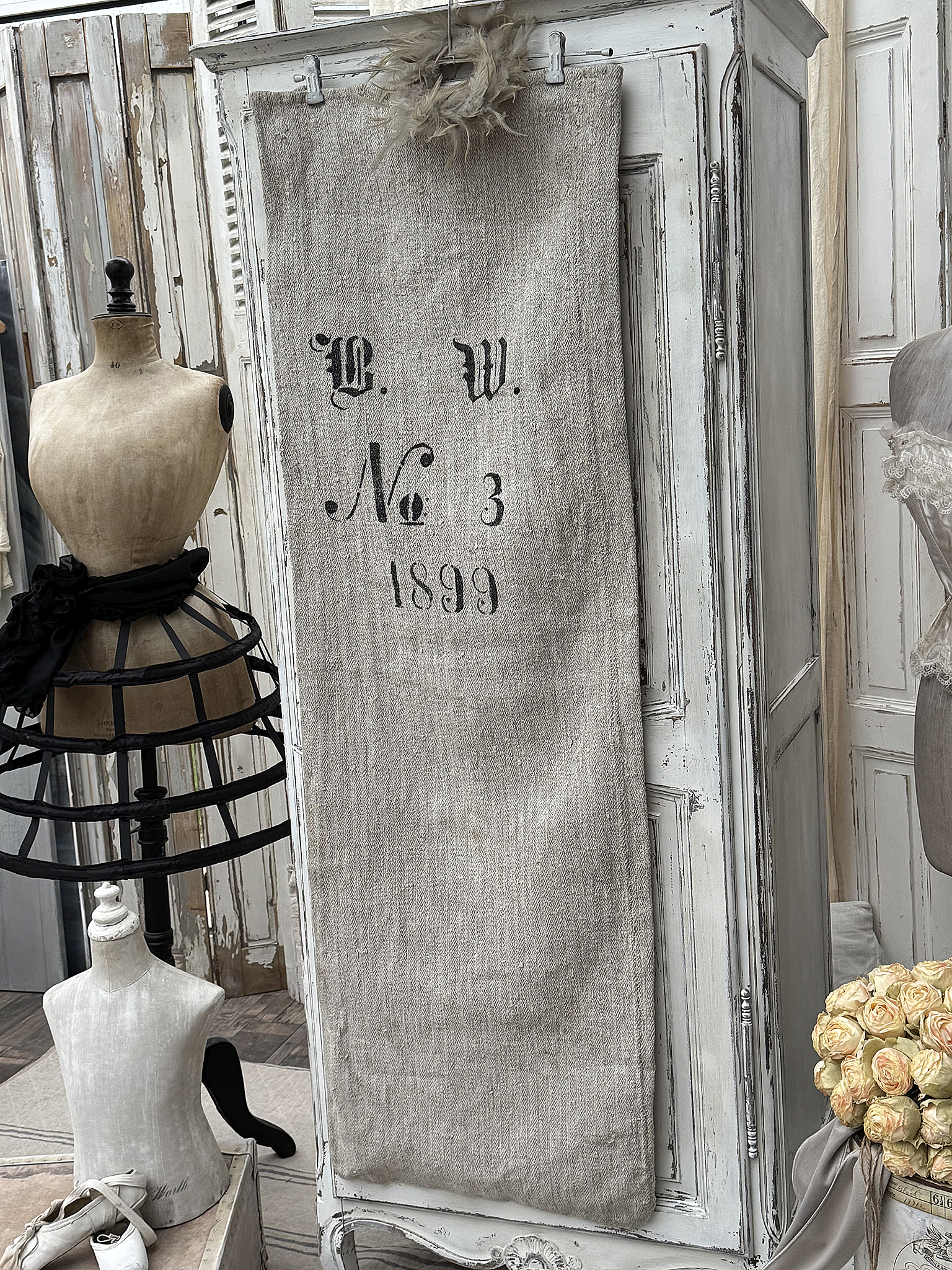 Ein Vintage Leinenbeutel mit der Aufschrift B.W. No 3 1899, kreativ dekoriert neben Mannequins