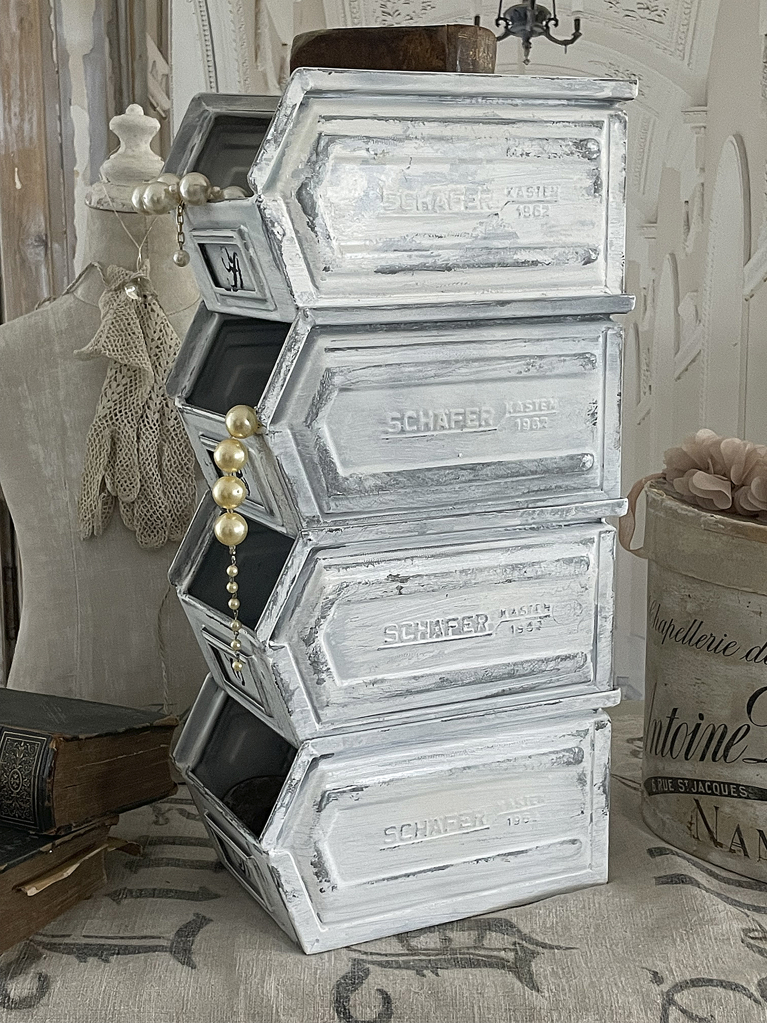 Stapelbare Aufbewahrungskästen im Vintage-Stil Decorative vintage-style stackable storage boxes with pearl chain accents.