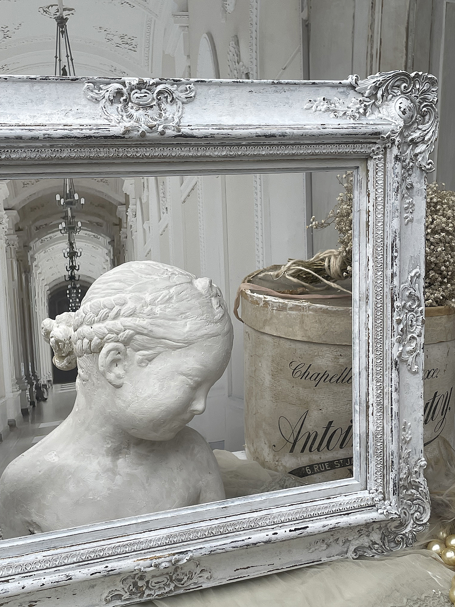 Elegante Bildfassung mit Skulptur und antiken Accessoires Weißer Rahmen mit einer Statue eines Kindes, dekoriert mit antiken Objekten.
