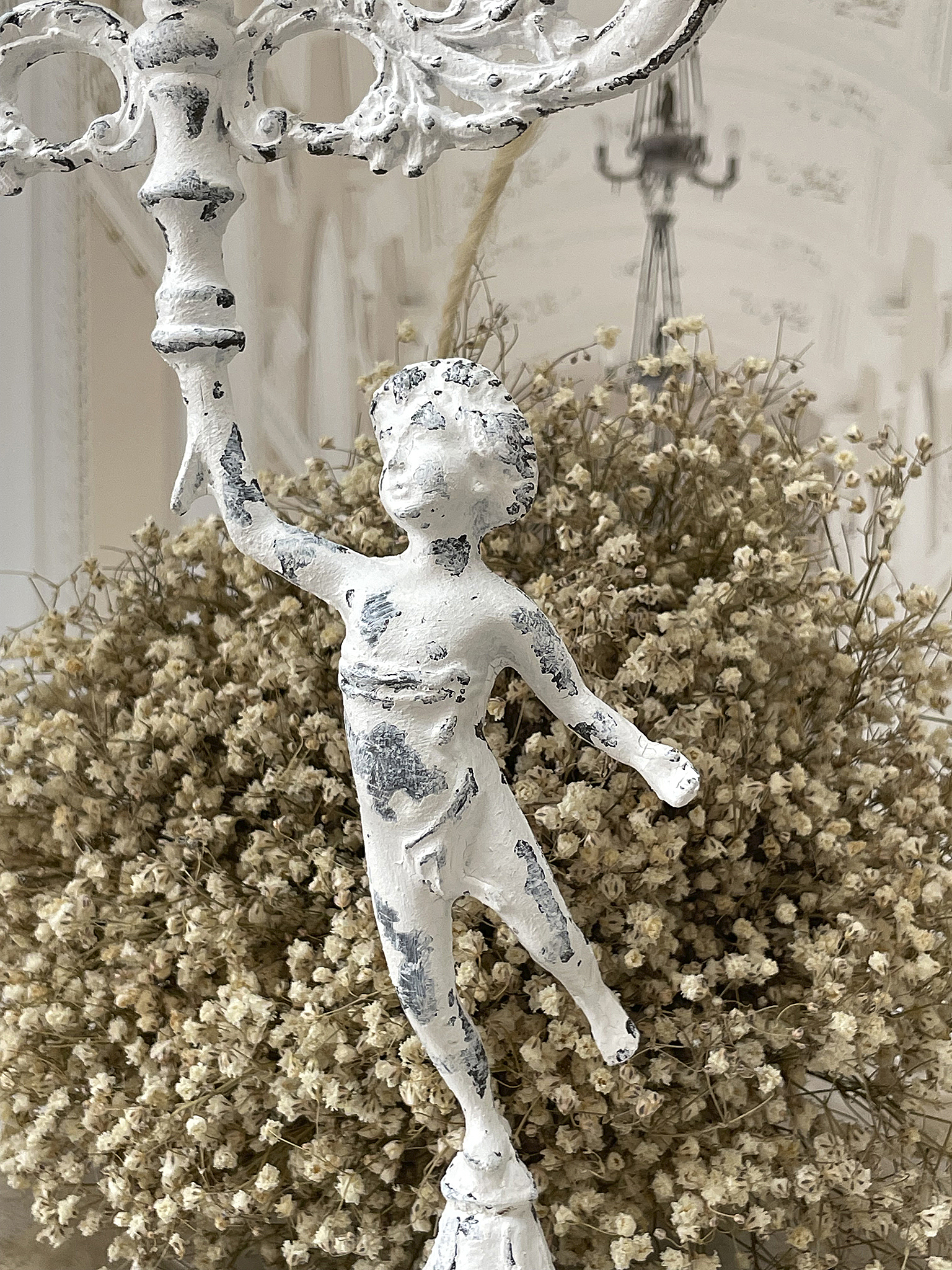 Dekorativer Ständer mit Engelfigur und Trockenblumen Kunstvoller Ständer mit einer weißen Engelfigur vor einem Hintergrund aus Trockenblumen