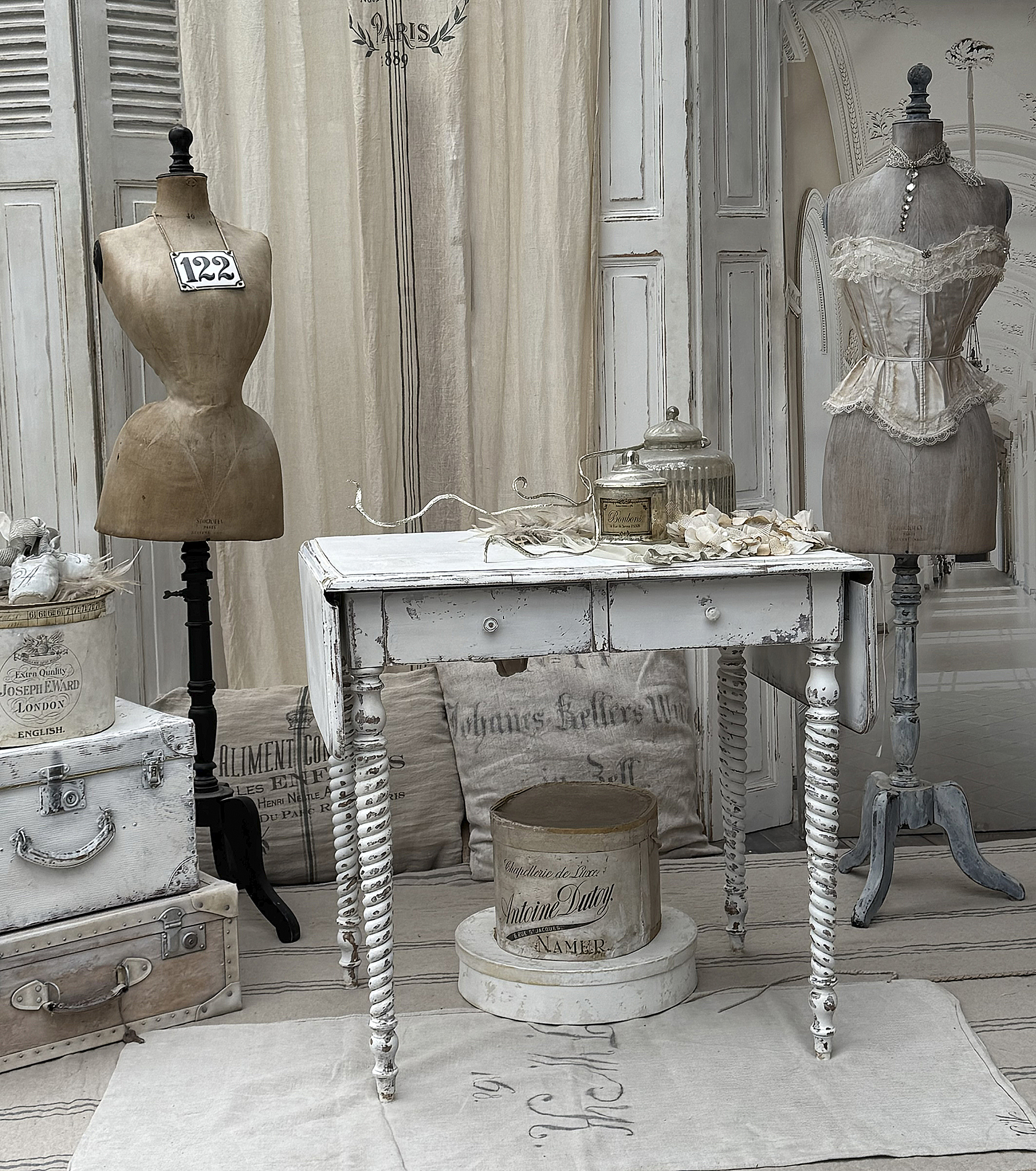 Detailansicht eines weißen Tisches im Shabby Chic Stil mit vintage Schneiderpuppen und Dekoration.