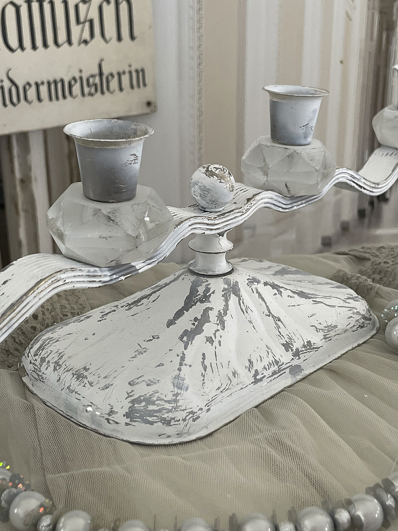 Eleganter Kerzenhalter in Vintage-Optik aus Metall Detaillierte Ansicht eines weißen Kerzenhalters mit geschwungener Form und klaren Kerzenhaltern