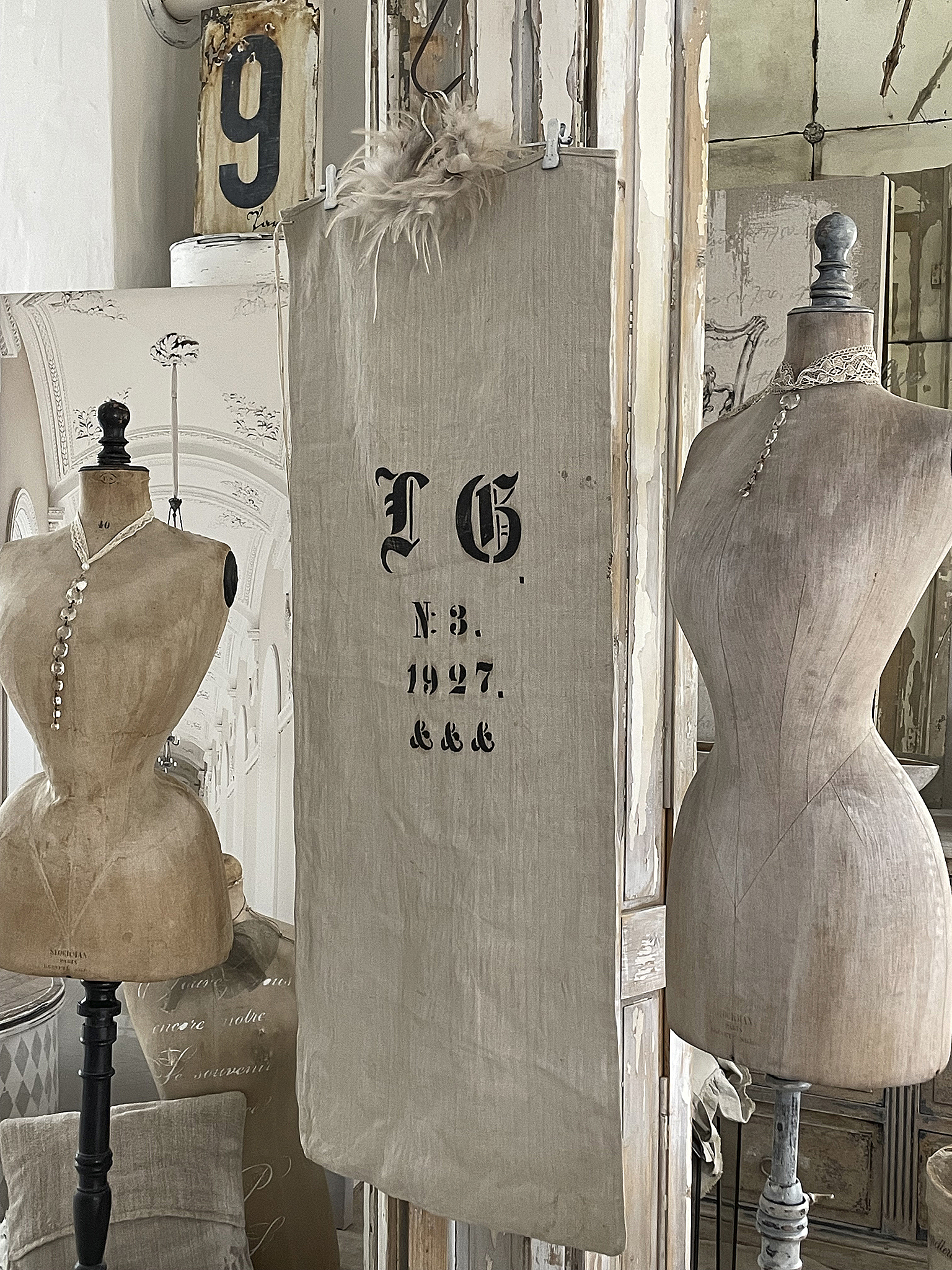 Stilvolles Dekor von Vintage-Mannequins und antikem Textil Vintage-Mannequins und ein dekorativer Stoff mit alten Schriftzeichen in einem stilvollen Raum