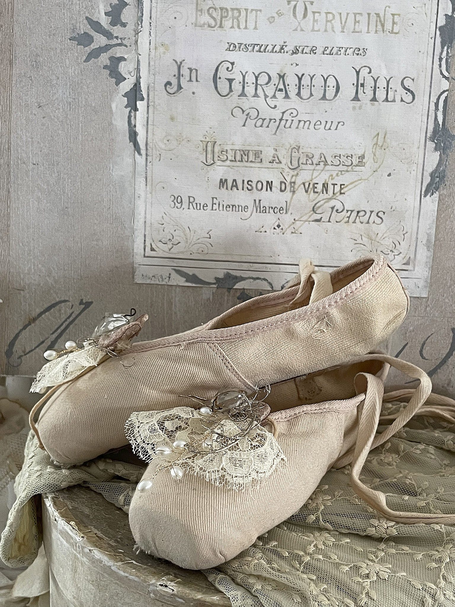 Elegante Ballettschuhe mit Schmuckdetail auf einem Vintage-Stoff Schöne Ballettschuhe mit Spitze und Perlen auf einem antiken Tisch