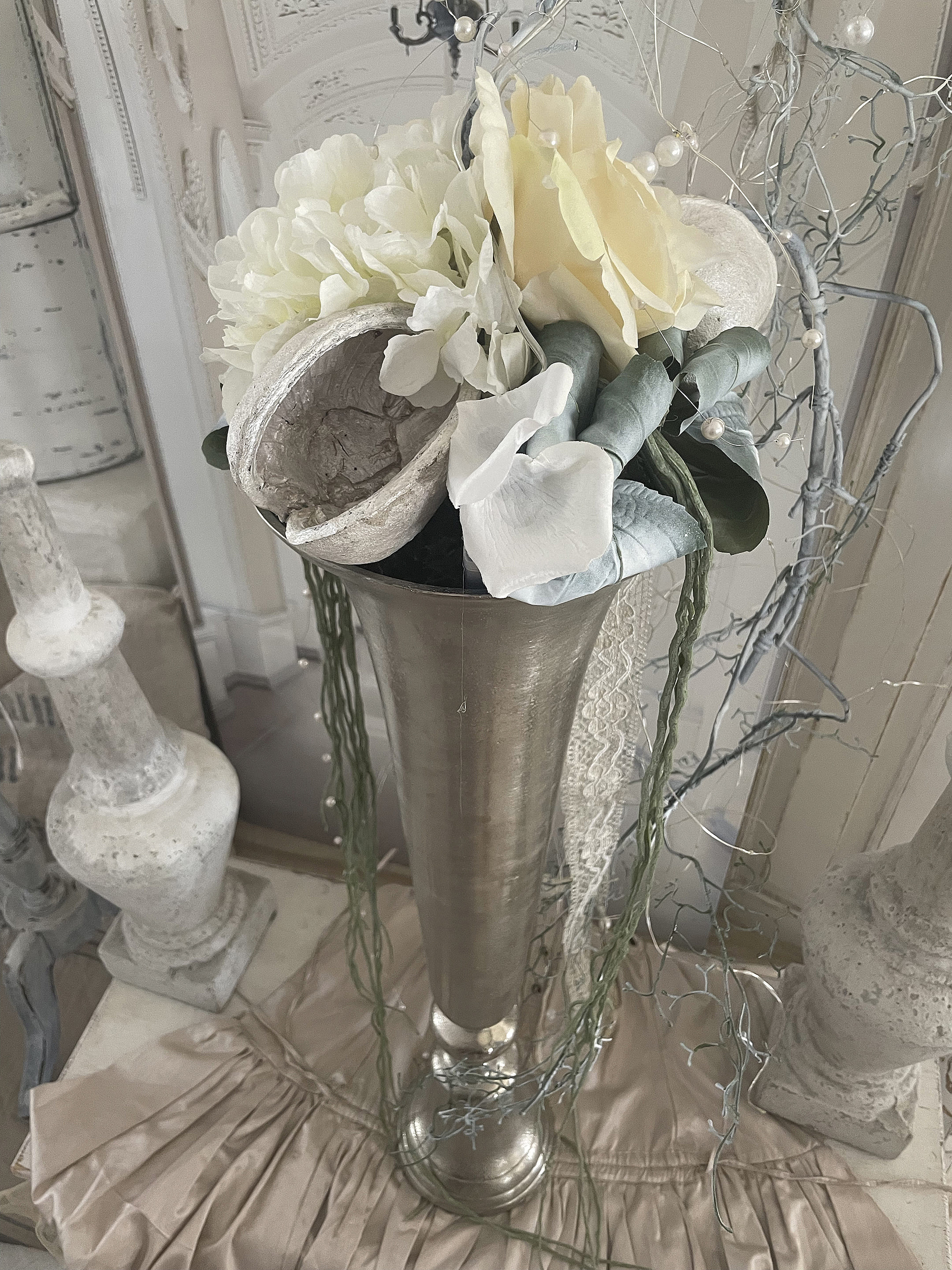Blumenarrangement in einer silbernen Vase, verziert mit stilvollen Elementen und Kunstblumen