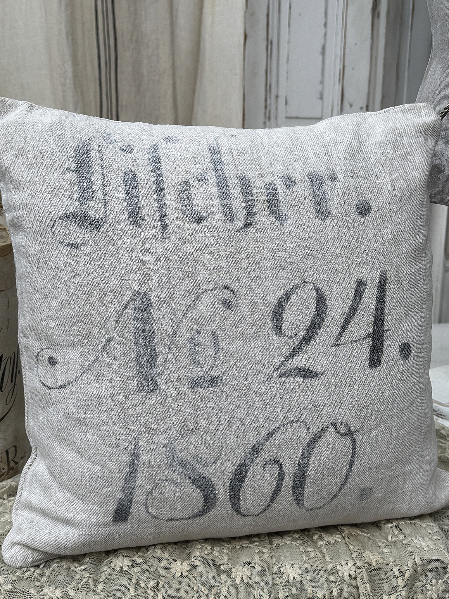 Kissen mit der Aufschrift "Lieder. Nr. 24. 1860" auf einem sanften grauen Hintergrund.