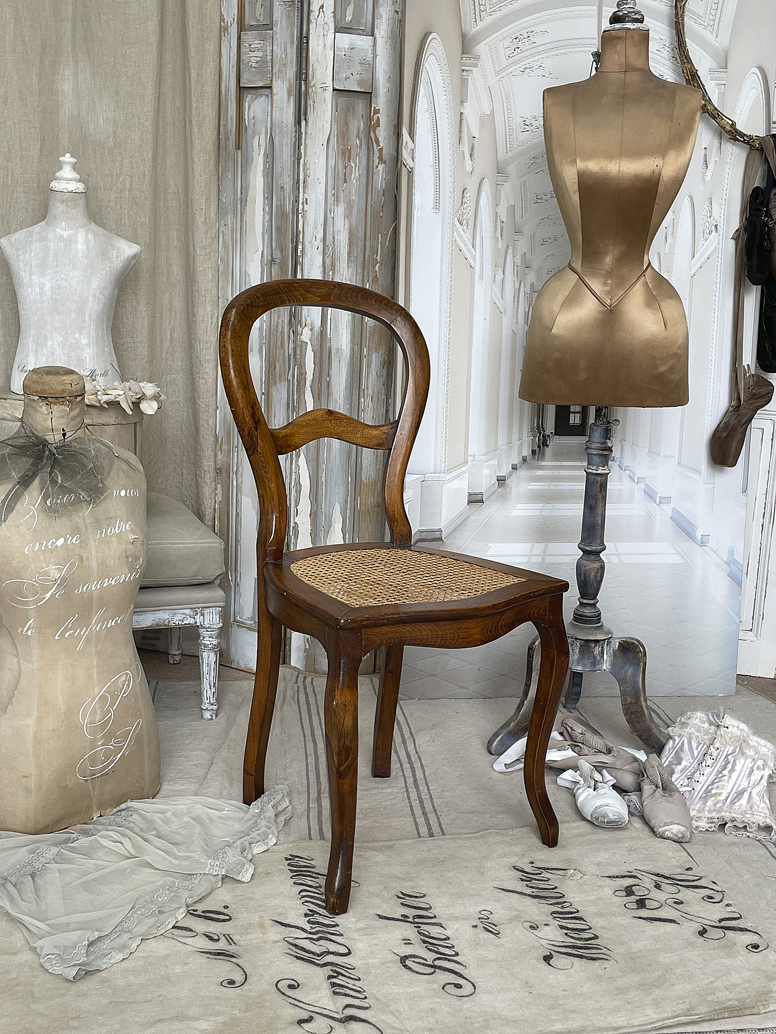 Eleganter Holzstuhl im skandinavischen Design mit einer Schneiderpuppe Holzstuhl mit geflochtener Sitzfläche, umgeben von Modeaccessoires und einer Schneiderpuppe.