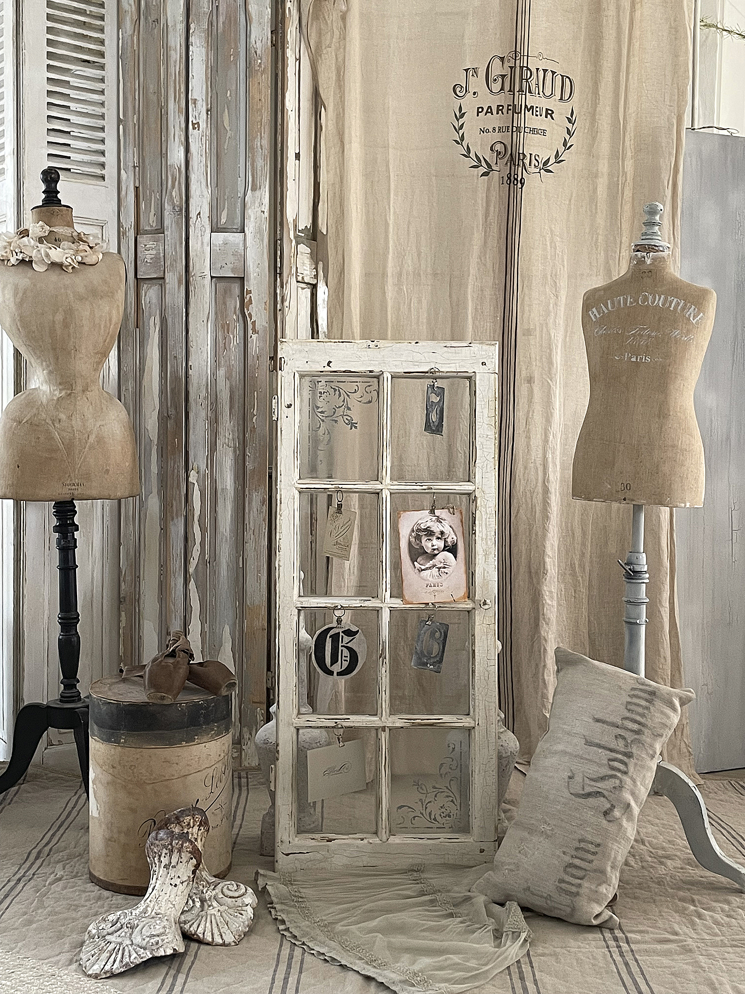 Stimmungsvolles Interior mit antiken Möbeln und Dekoration Ein eingerichteter Raum mit antiken Mannequins, einem alten Fenster, dekorativen Kissen und Vintage-Objekten.