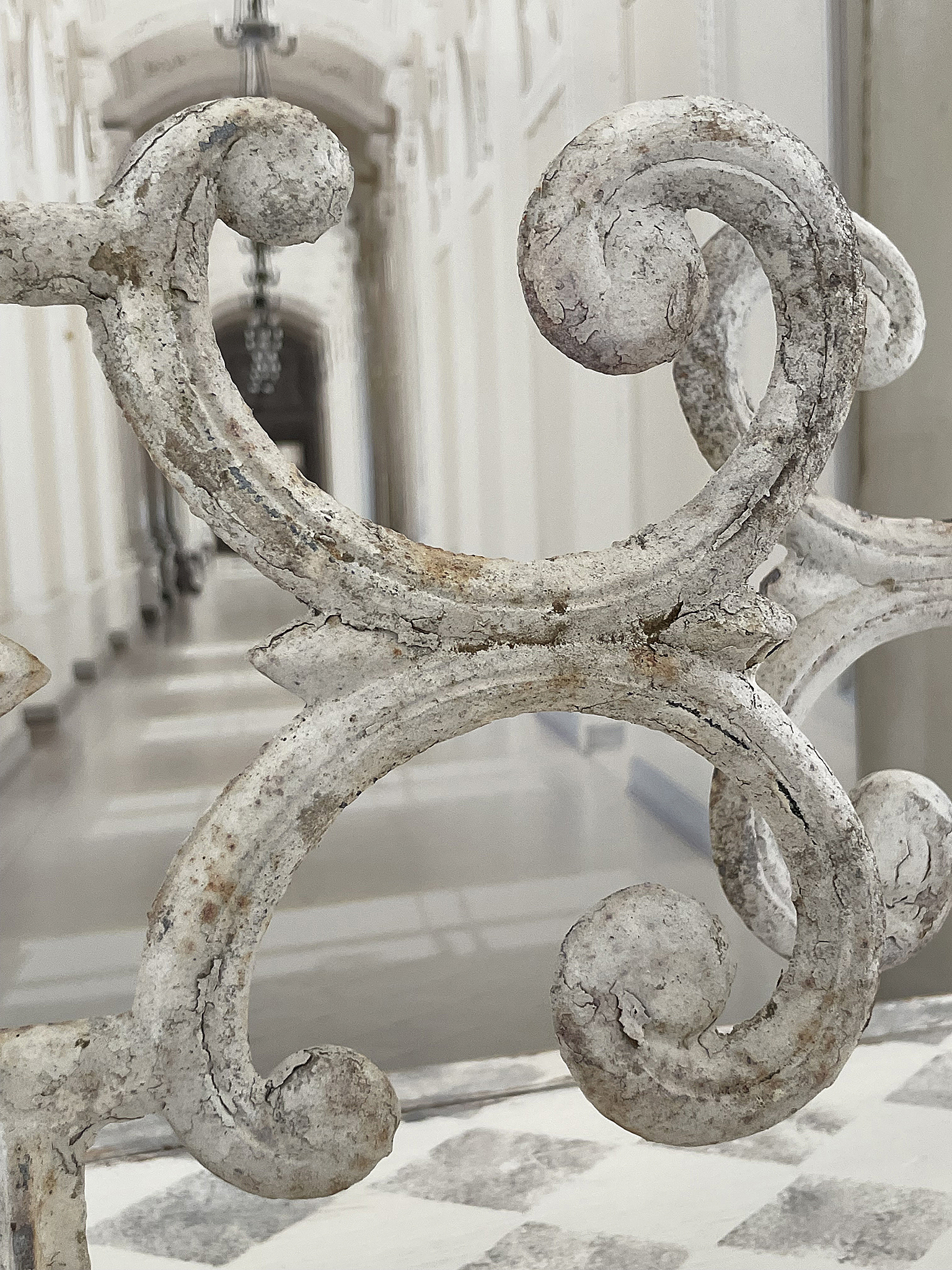 Detailansicht eines geschwungenen Metallgeländers in einem eleganten Innenraum geschwungenes, verziertes Metallgeländer mit Patina in einem hellen Innenraum