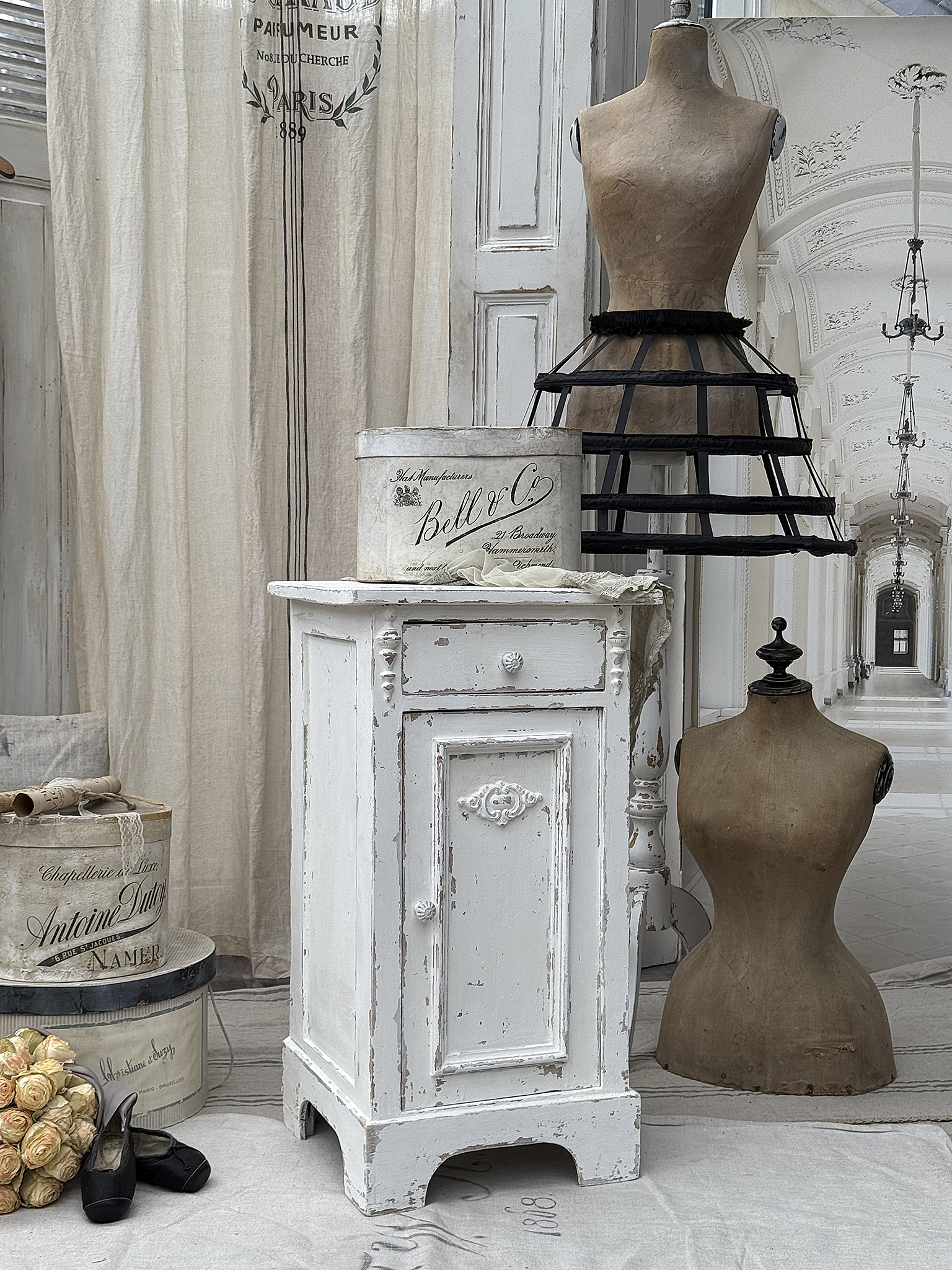 Vintage Möbelstücke für ein elegantes Zuhause Weißer vintage Beistelltisch neben einer Schneiderpuppe und dekorativen Boxen