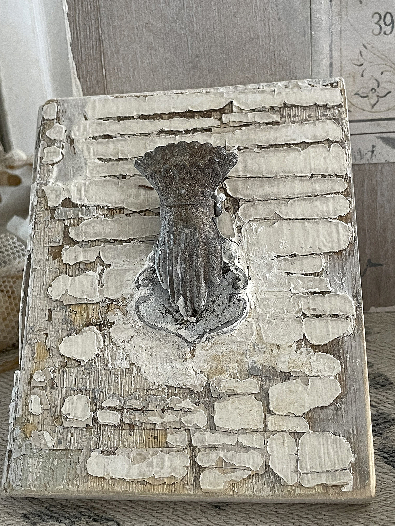 Antiker Wandgriff in Form einer Hand, montiert auf einer strukturierten Holzplatte