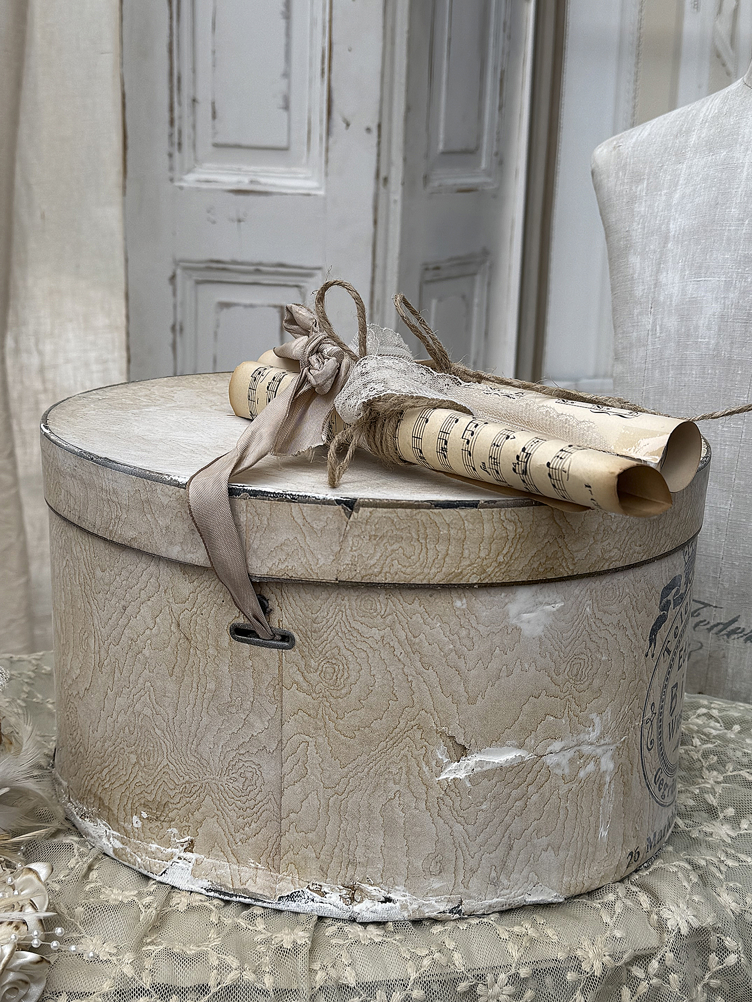 Dekorative Aufbewahrungsschachtel mit Notenrollen Runde alte Aufbewahrungsschachtel aus Holz mit zwei eingerollten Notenblättern und einer eleganten Schleife.