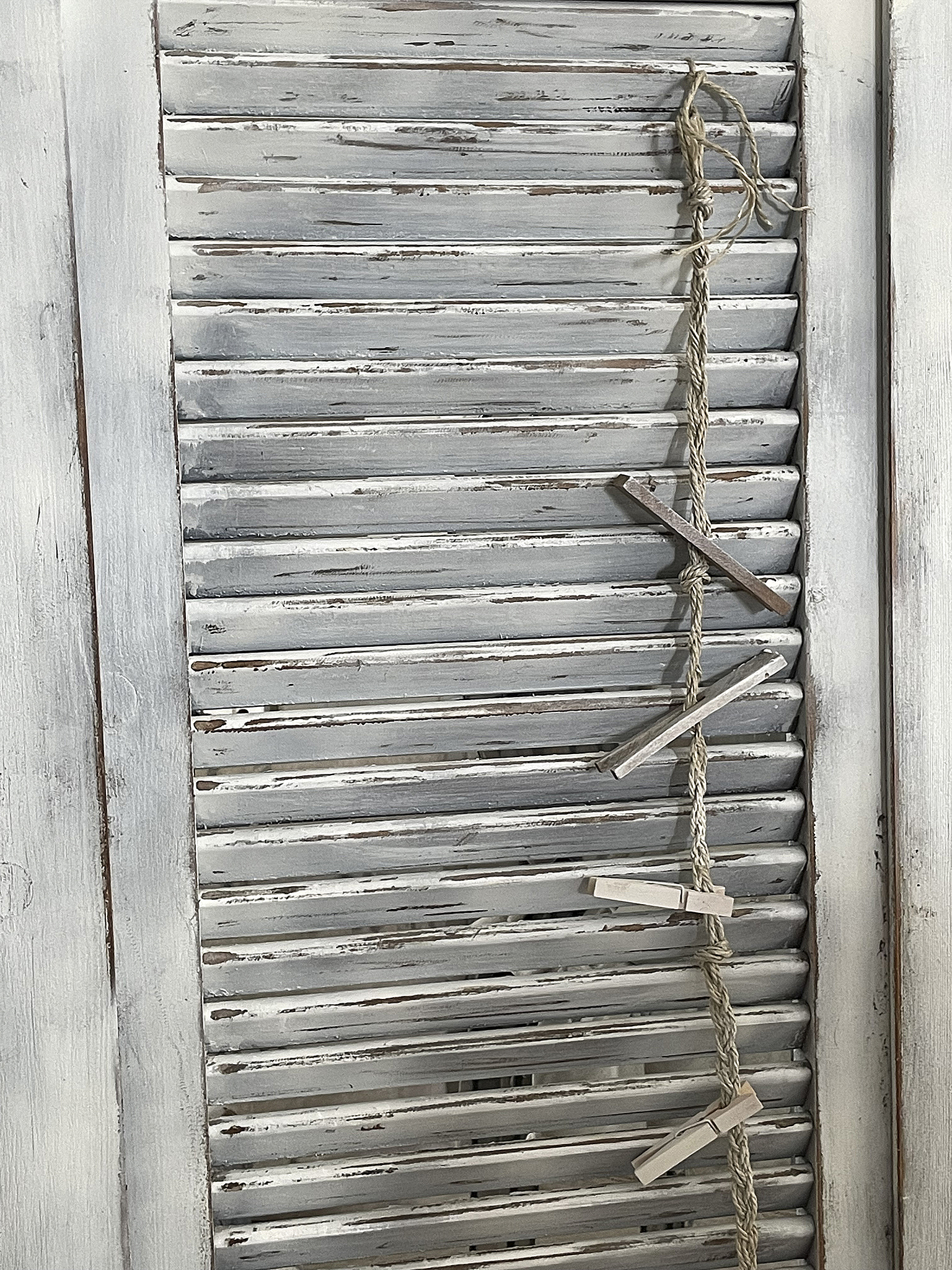 Rustikales Fensterläden-Design mit Wäscheklammern Detailaufnahme eines rustikalen Fensterladens mit Wäscheklammern und Schnur