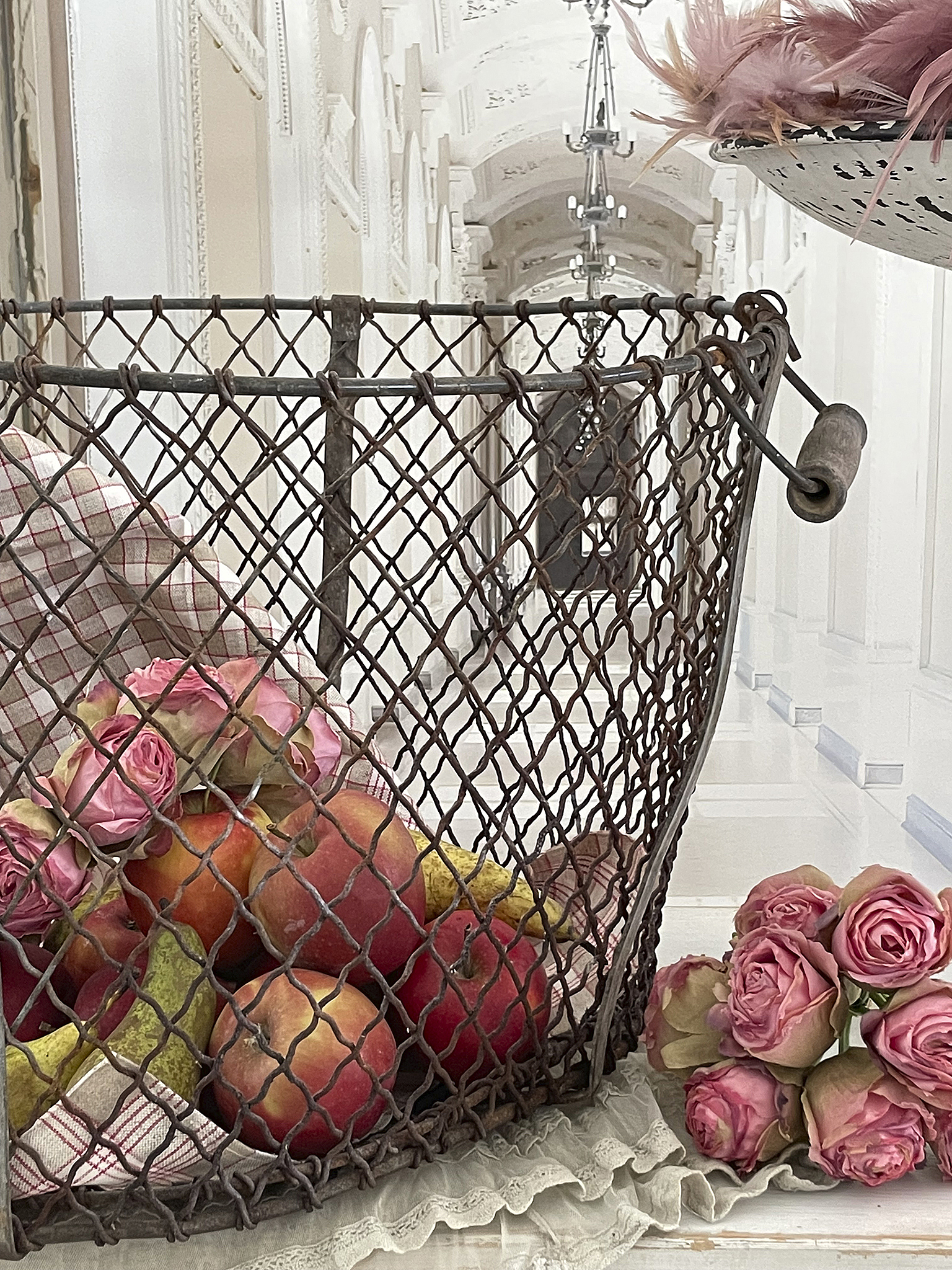 Vintage Obstkorb mit Rosen im elegantem Ambiente Ein nostalgischer Drahtkorb voller Obst und Rosengestecken in einem hellen Flur.
