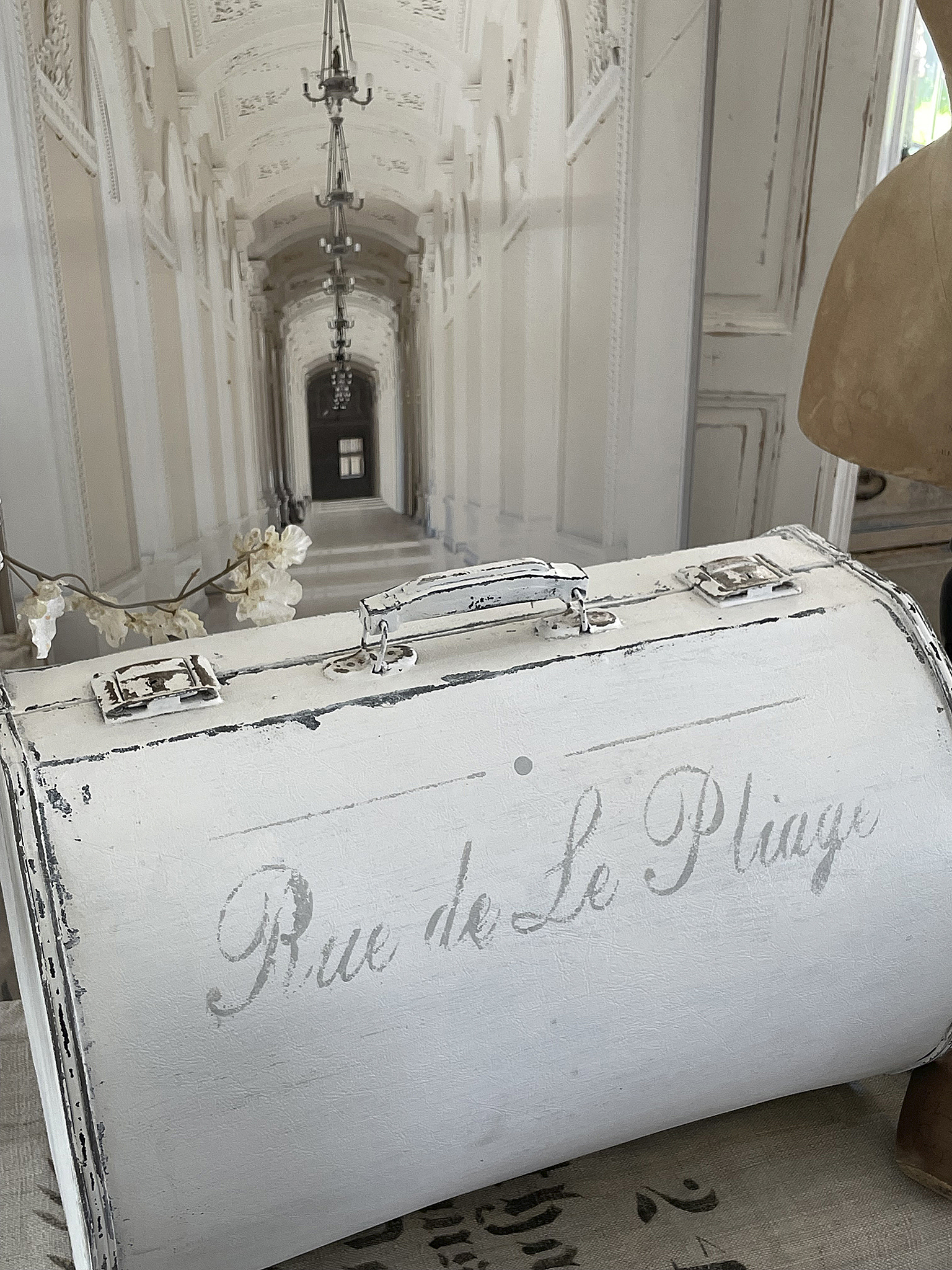 Vintage Koffer mit Aufschrift Rue de Le Plage auf dekorativem Hintergrund Dekorativer Vintage Koffer mit dem Schriftzug Rue de Le Plage, vor einem hellen, eleganten Hintergrund.