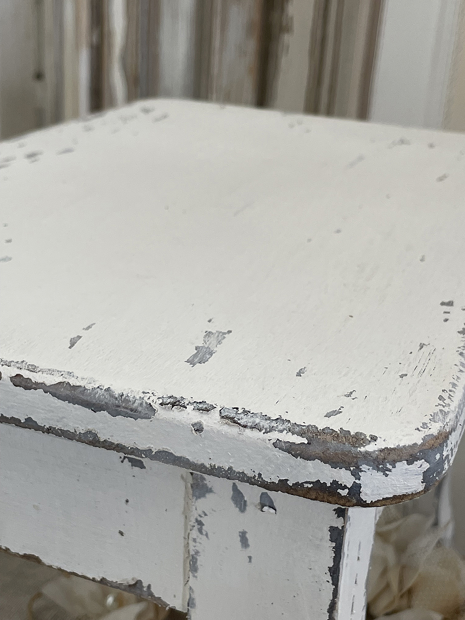 Ein schöner, vintage weißer Holztisch mit Patina Detailaufnahme eines weißen Holztisches mit abblätternder Farbe und rustikalem Charme