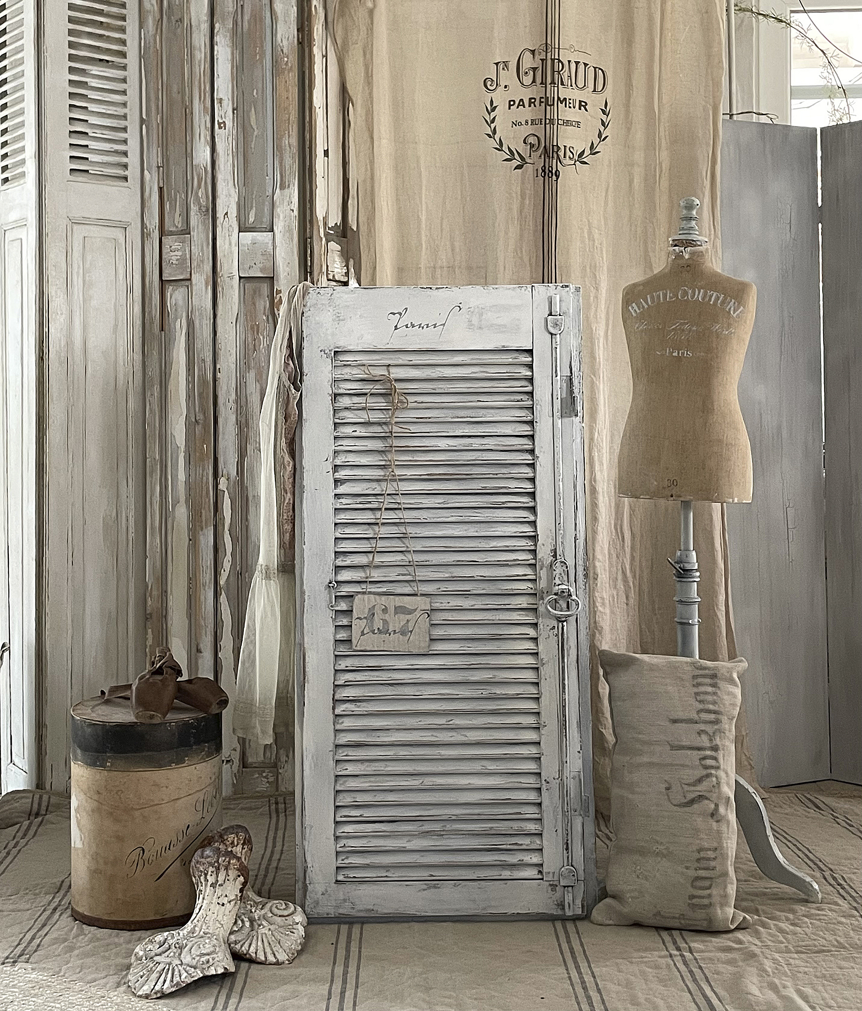 Dekorative Vintage-Inneneinrichtung mit Shabby-Chic-Elementen Stilvolles Wohnambiente mit einem weißen Fensterladen, einer Schneiderpuppe und antiken Accessoires.
