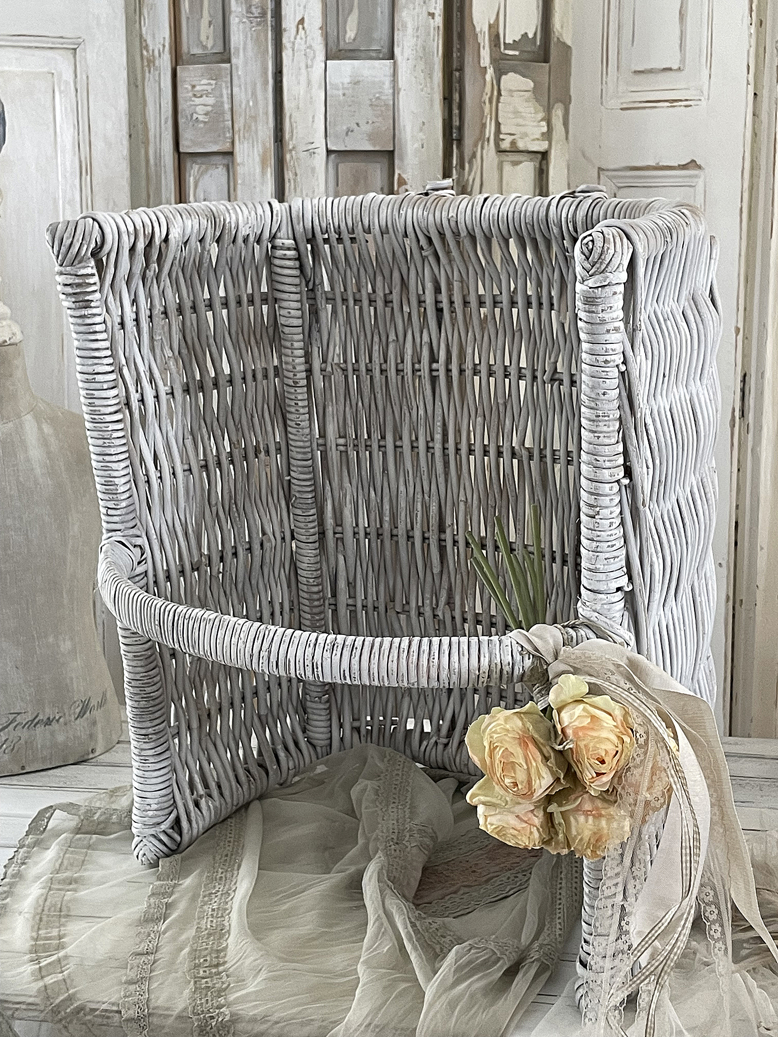 Heller Weidenkorb mit Blumen und elegantem Tuch Dekorativer Weidenkorb in Weiß mit Rosen und transparenter Stoffdekoration