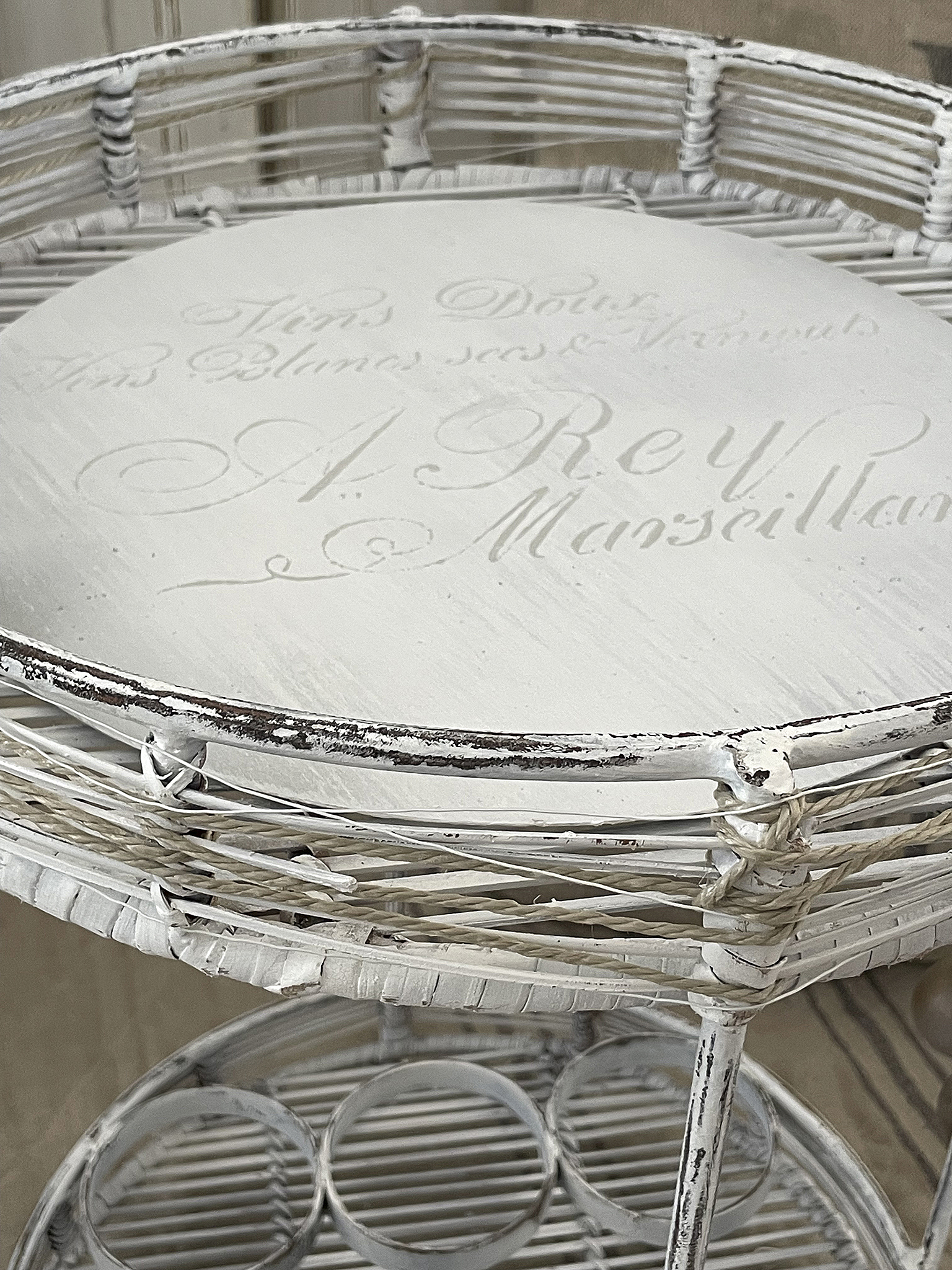 Eleganter runder Beistelltisch aus weißem Korbgeflecht mit Vintage-Schriftzug Runder Korbtisch in Weiß mit dekorativem Schriftzug A. Rey Marseille