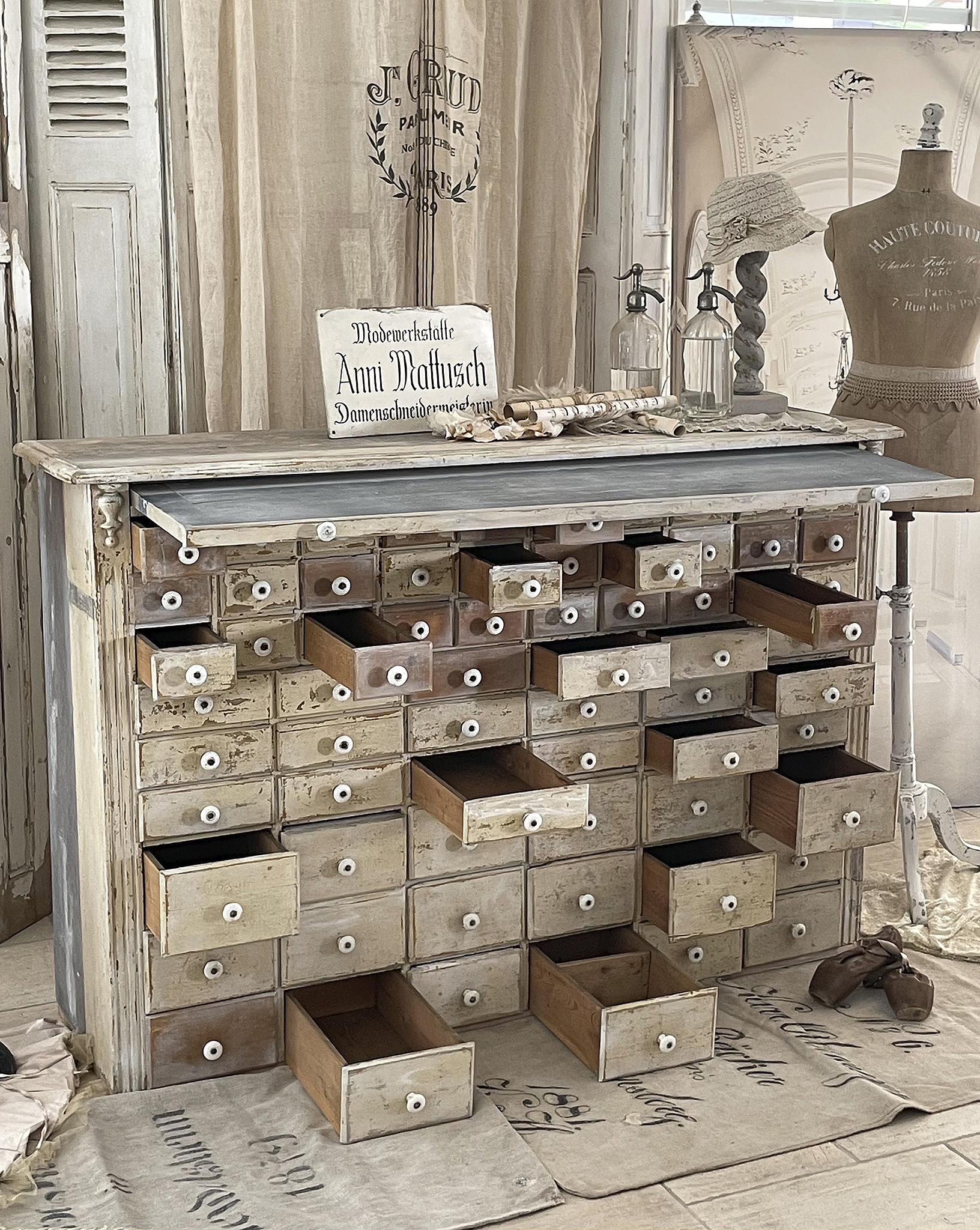 Detailansicht eines vintage Kommodenmöbels mit zahlreichen offenen und geschlossenen Schubladen in einer Modewerkstatt.