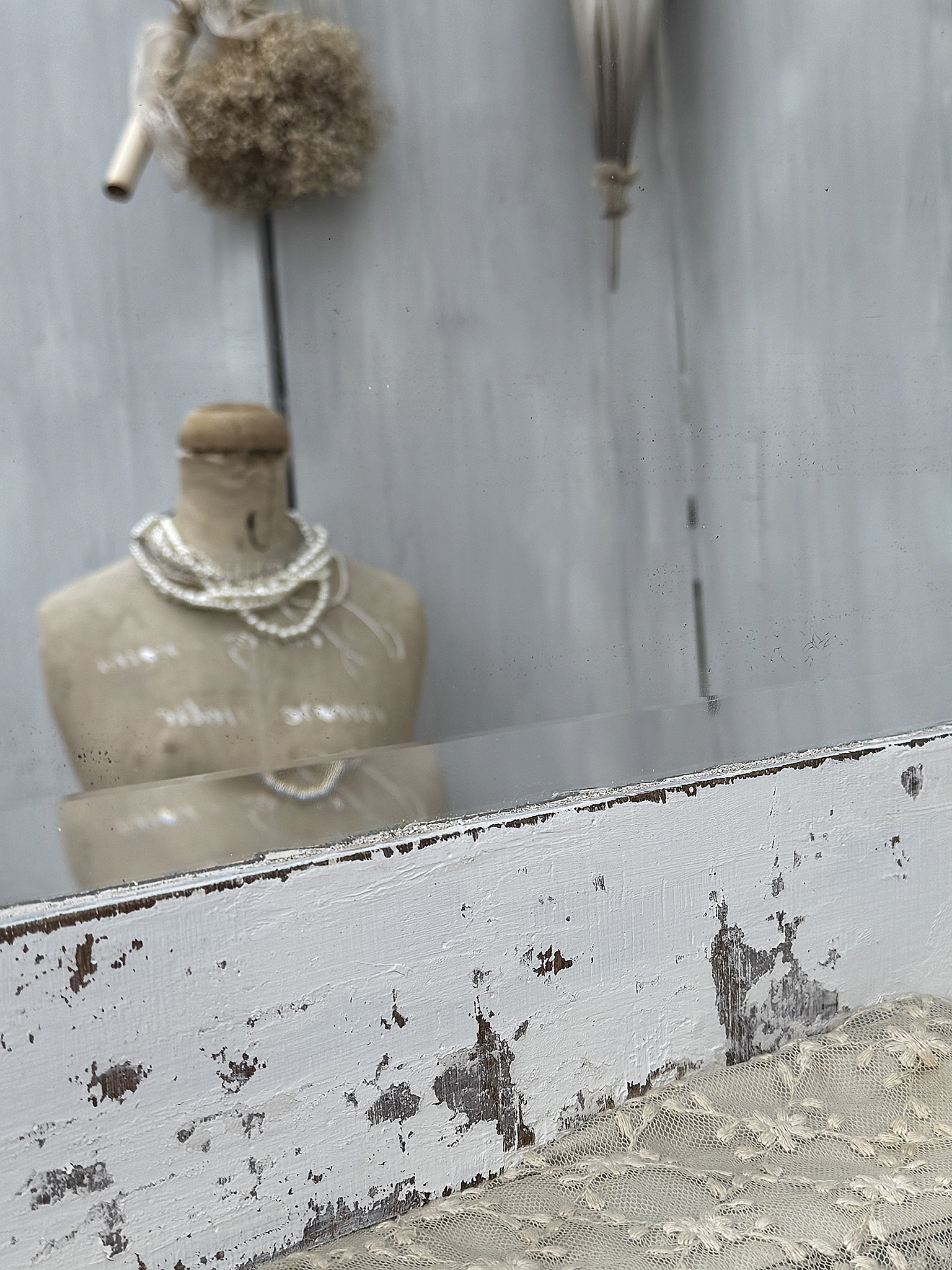 Eleganter Schaufensterartikel mit vintage Kleidung und Perlenkette Mannequin mit Perlenkette vor einem Spiegel und dekorativen Elementen