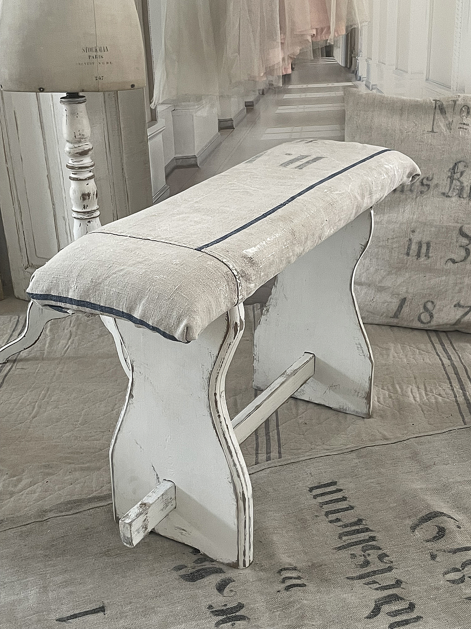 Vintage Hocker mit gepolstertem Sitz und weißem Holzrahmen Alter Hocker mit gepolsterter Sitzfläche, ideal für stilvolle Inneneinrichtungen