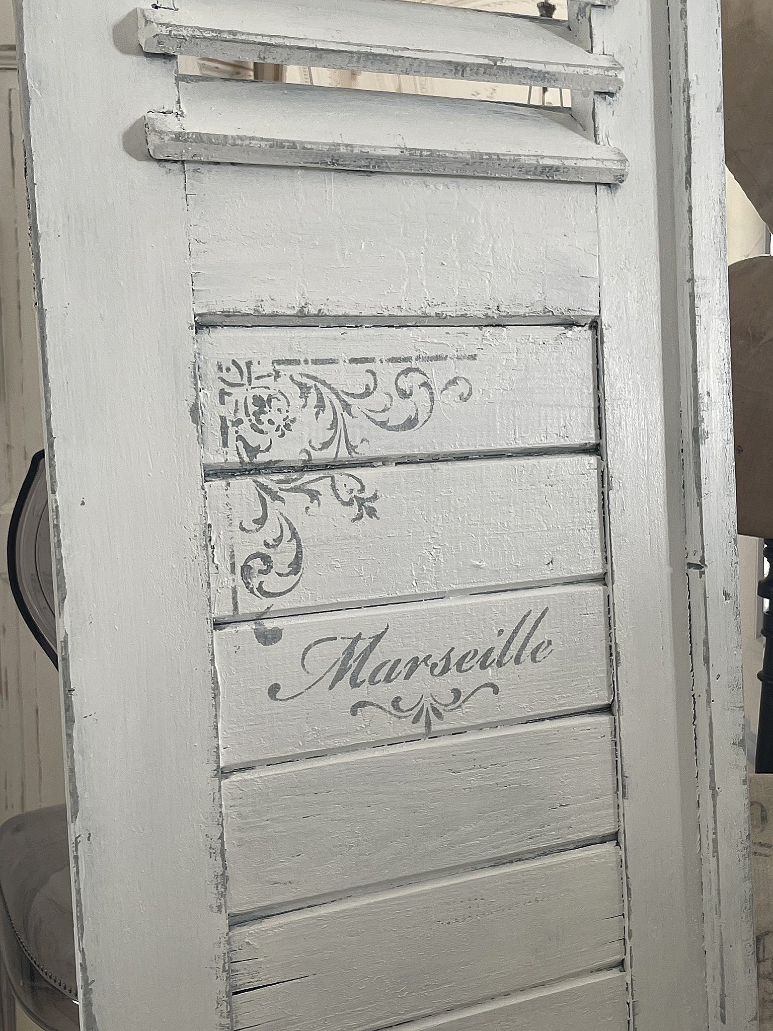 Dekorative Holzlatte mit dem Schriftzug Marseille Dekorative Holzlatte in grau mit verschnörkeltem Design und dem Wort Marseille