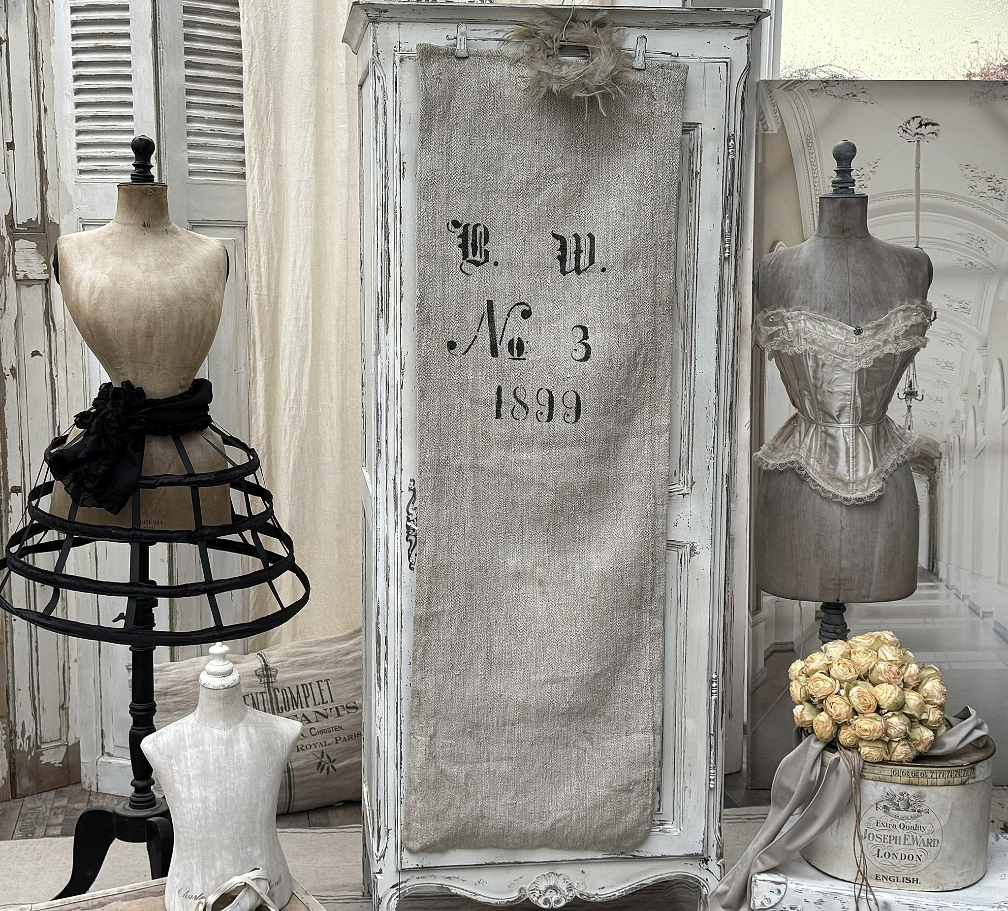 Ein vintage Schneideratelier mit mehreren Mannequins, einem antiken Schrank und einer Blumendekoration.