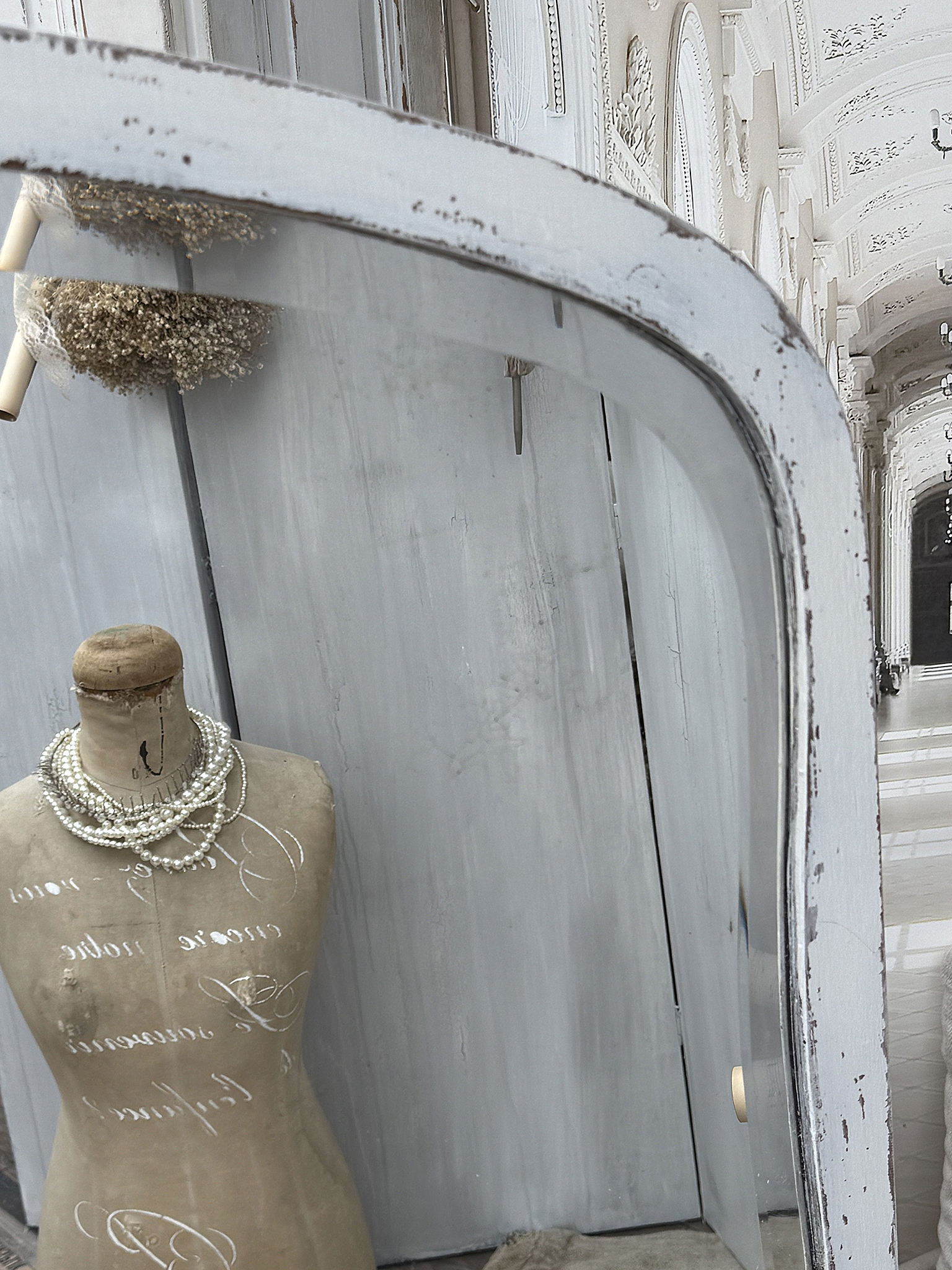 Elegante Schaufensterpuppe mit Perlenschmuck vor einem antiken Spiegel Schaufensterpuppe mit Perlenschmuck in einem stilvollen Ambiente, Spiegel reflektiert den Raum.