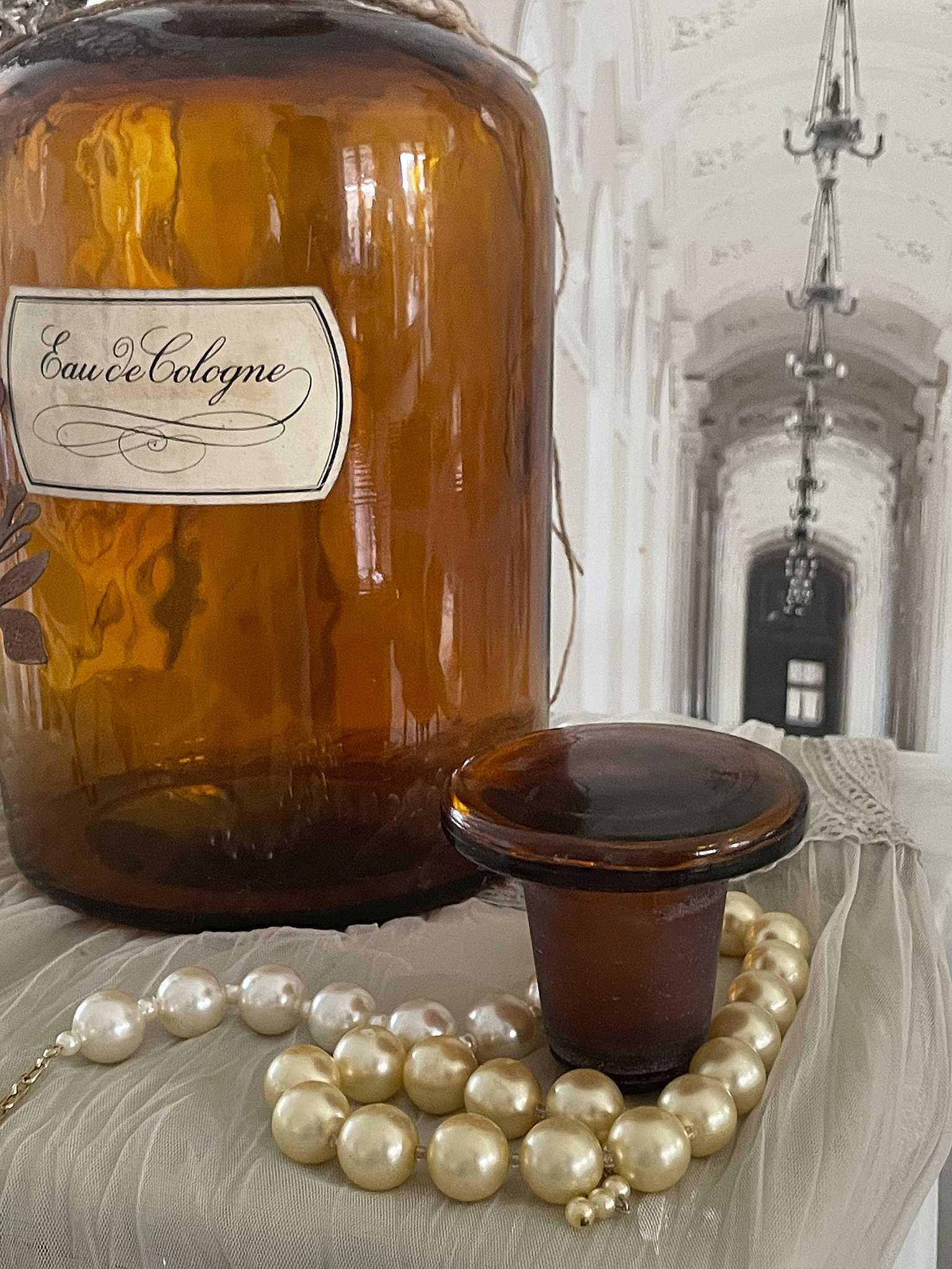 Antike Eau de Cologne Flasche mit Perlenkette und Kerzenhalter Vintage Eau de Cologne Flasche mit einer Perlenkette und einem Kerzenhalter auf einem eleganten Hintergrund
