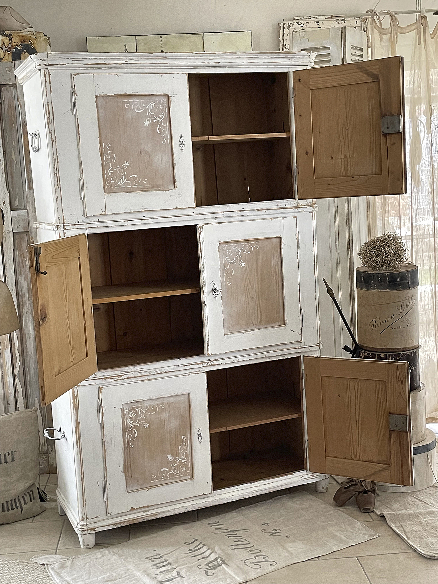 Weißer Schrank im Vintage-Stil mit dekorativen Elementen und offenem Stauraum