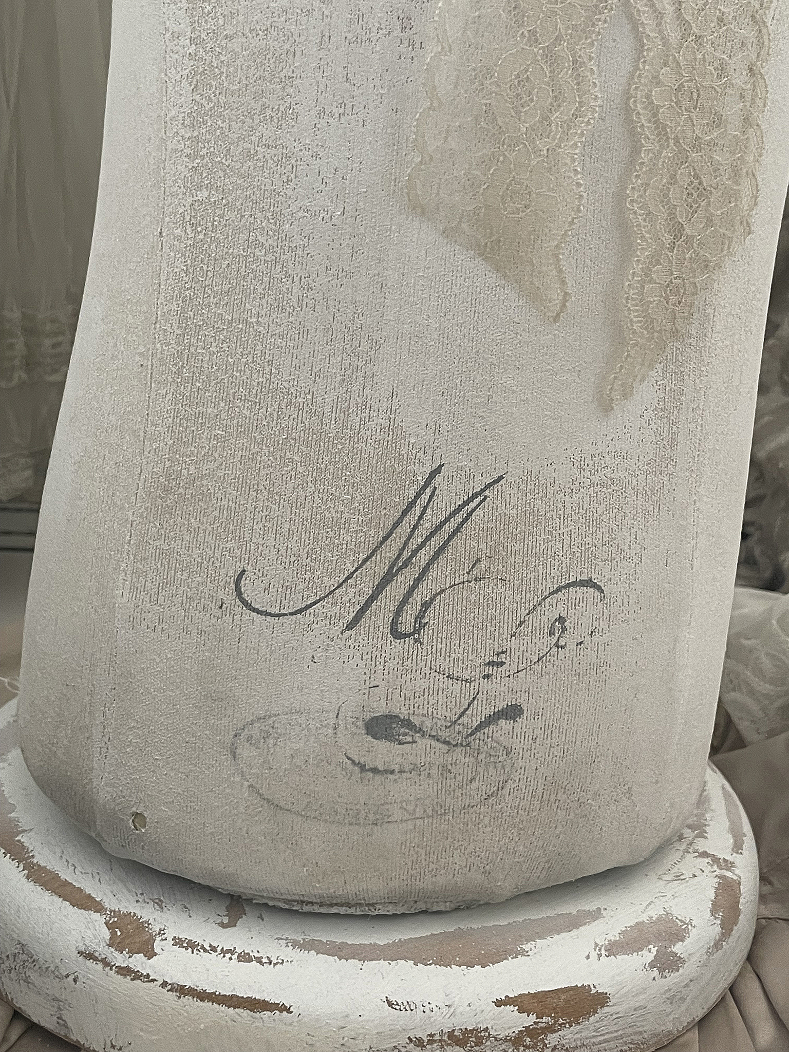 Detailaufnahme eines vintage-inspirierten Dekoobjekts mit elegantem Schriftzug Dekoratives Objekt mit zartem Spitzenband und handschriftlichem Schriftzug auf einer weißen Oberfläche