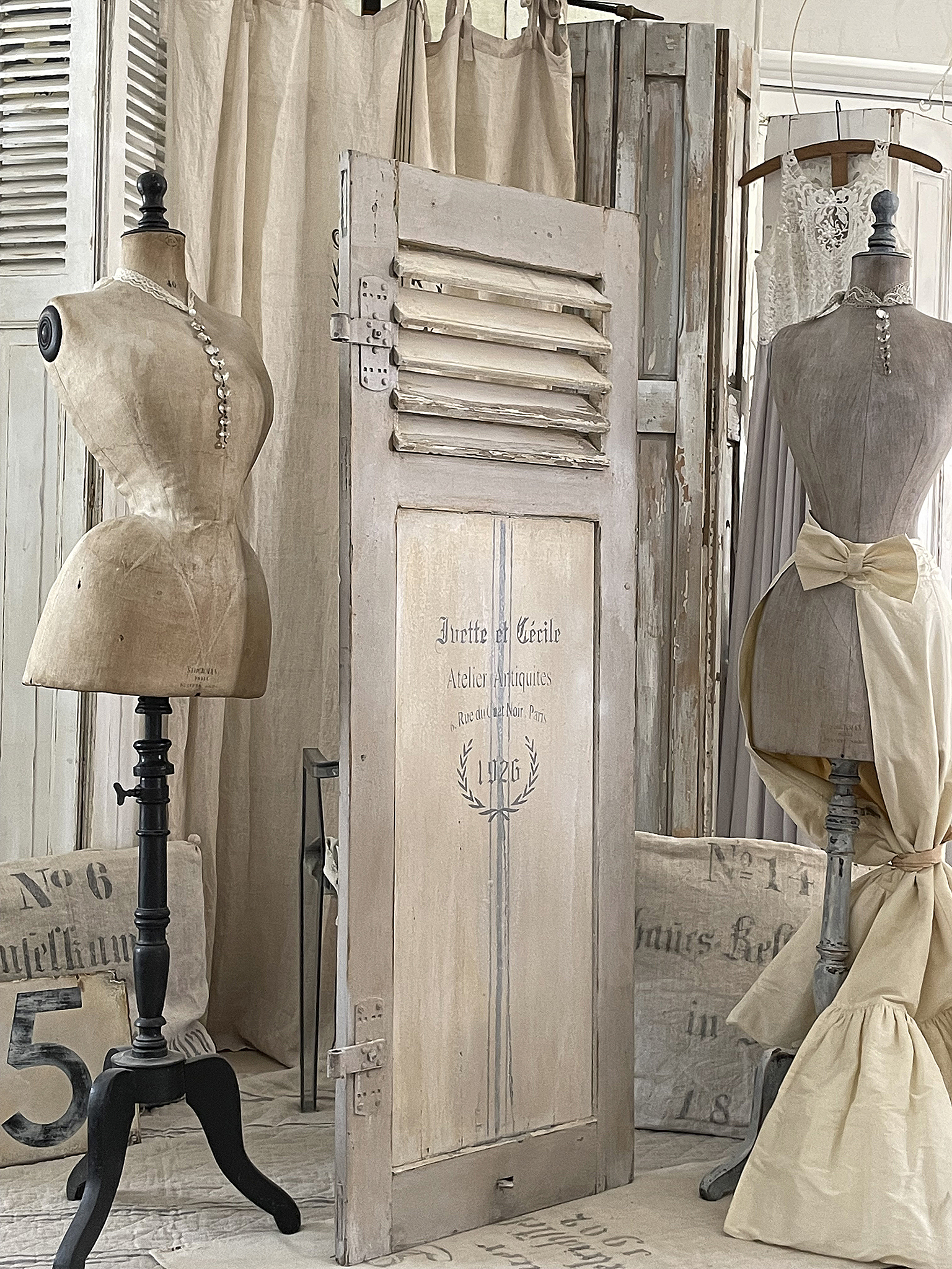 Elegante Vintage Einrichtung mit Schneiderpuppen und Türen Zwei Schneiderpuppen und eine antike Tür in einem stilvollen Vintage-Raum.