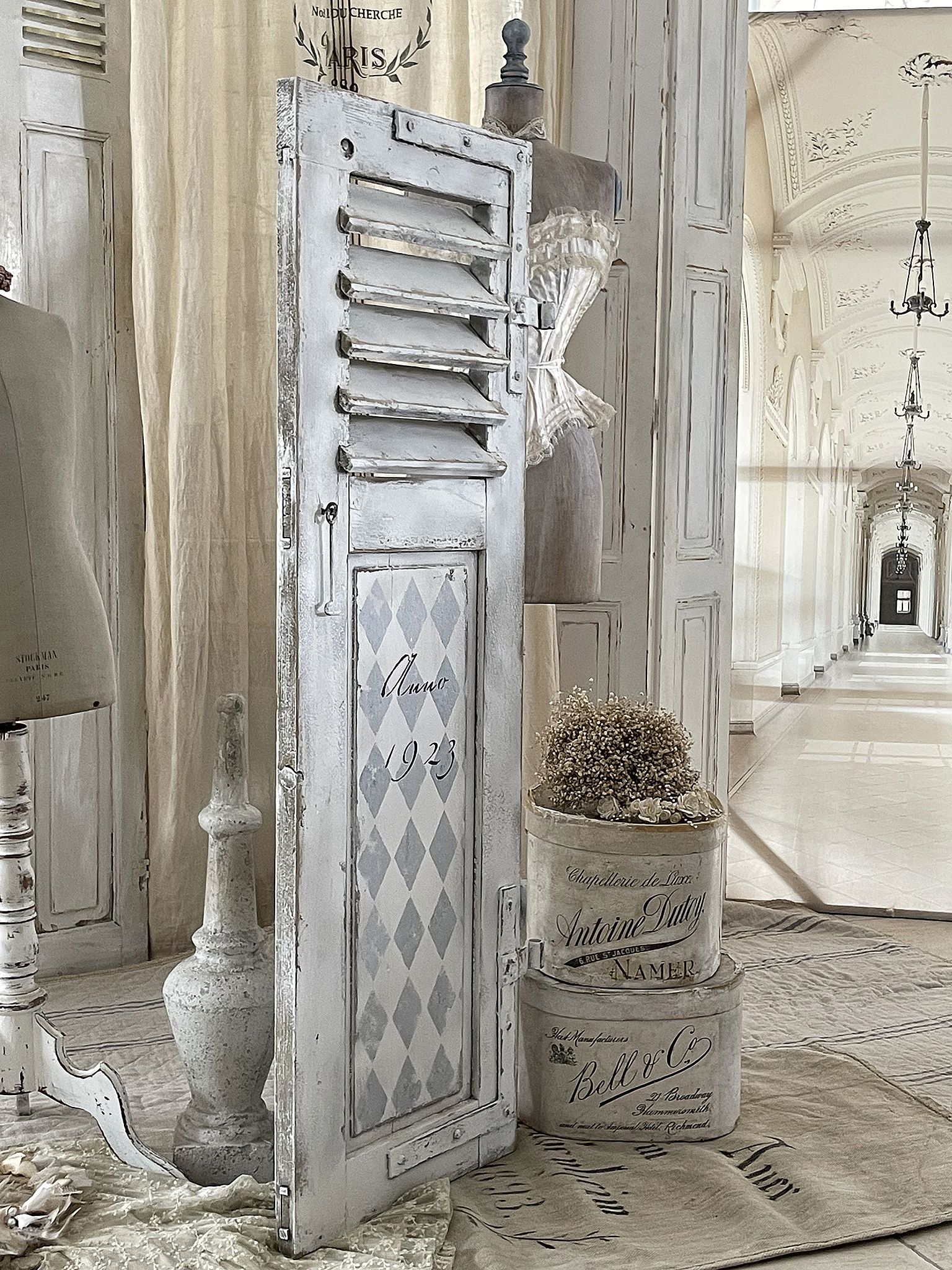 Antike Dekoration mit Shutter und Vintage-Accessoires Ein nostalgischer Shutter aus dem Jahr 1923, flankiert von einem Mannequin und dekorativen Boxen.