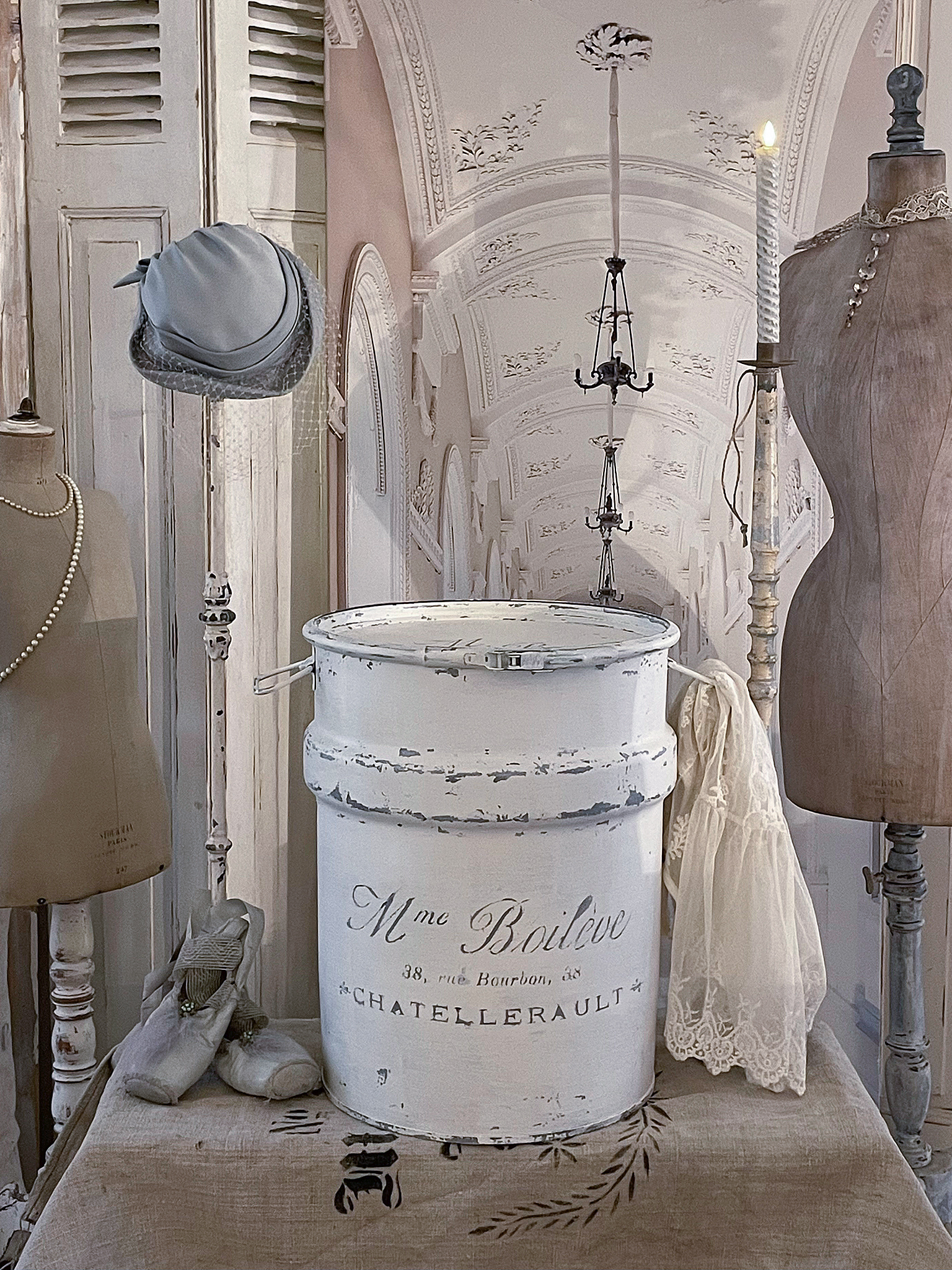 Vintage Dekoration mit Kanister, Hut und Kleid Dekorierter Tisch mit vintage Kanister, einem Hut, einem Kleid und weiteren Accessoires in einem eleganten Raum.