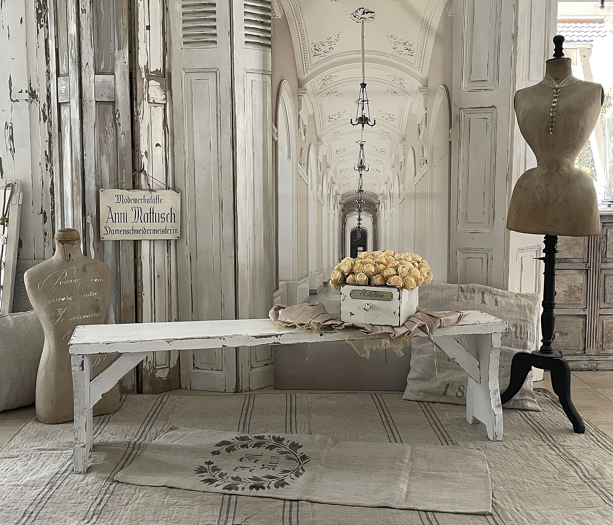 Rustikaler Holztisch mit Blumendekoration in vintage-inspirierter Umgebung Essbereich mit shabby-chic Holztisch, eleganten Rosen und vintage Schneiderpuppen
