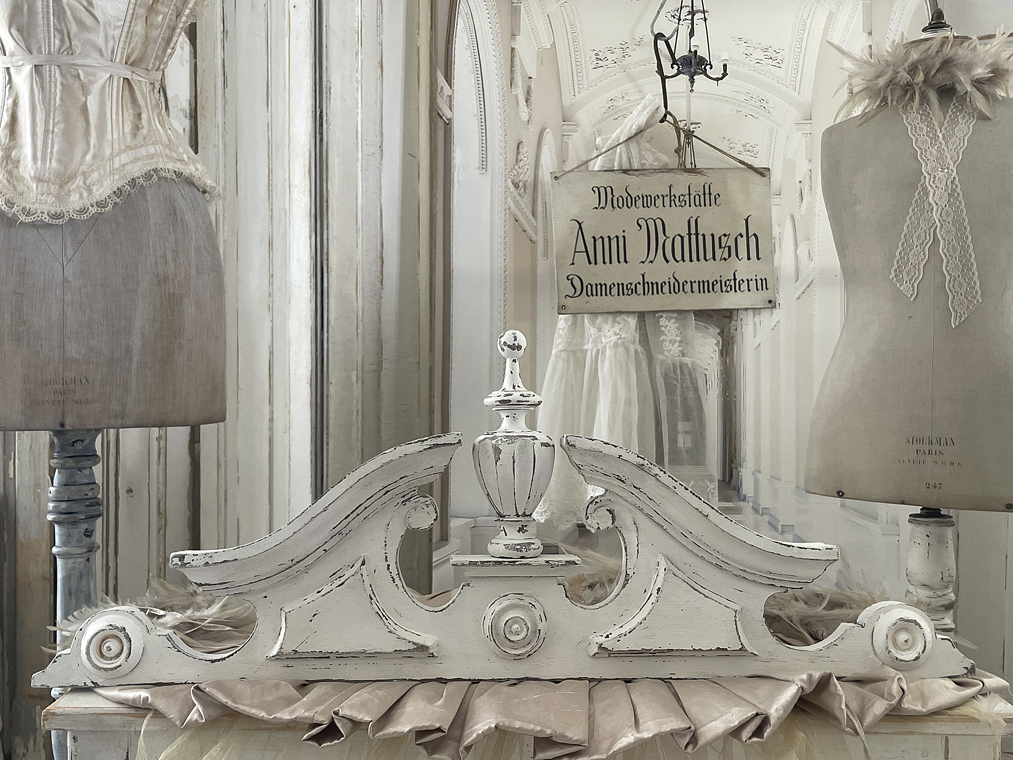 Elegante Schneiderwerkstatt mit historischen Details Historische Schneiderwerkstatt mit Schneiderpuppen und einem Ausschilderungsschild von Anni Mattusch