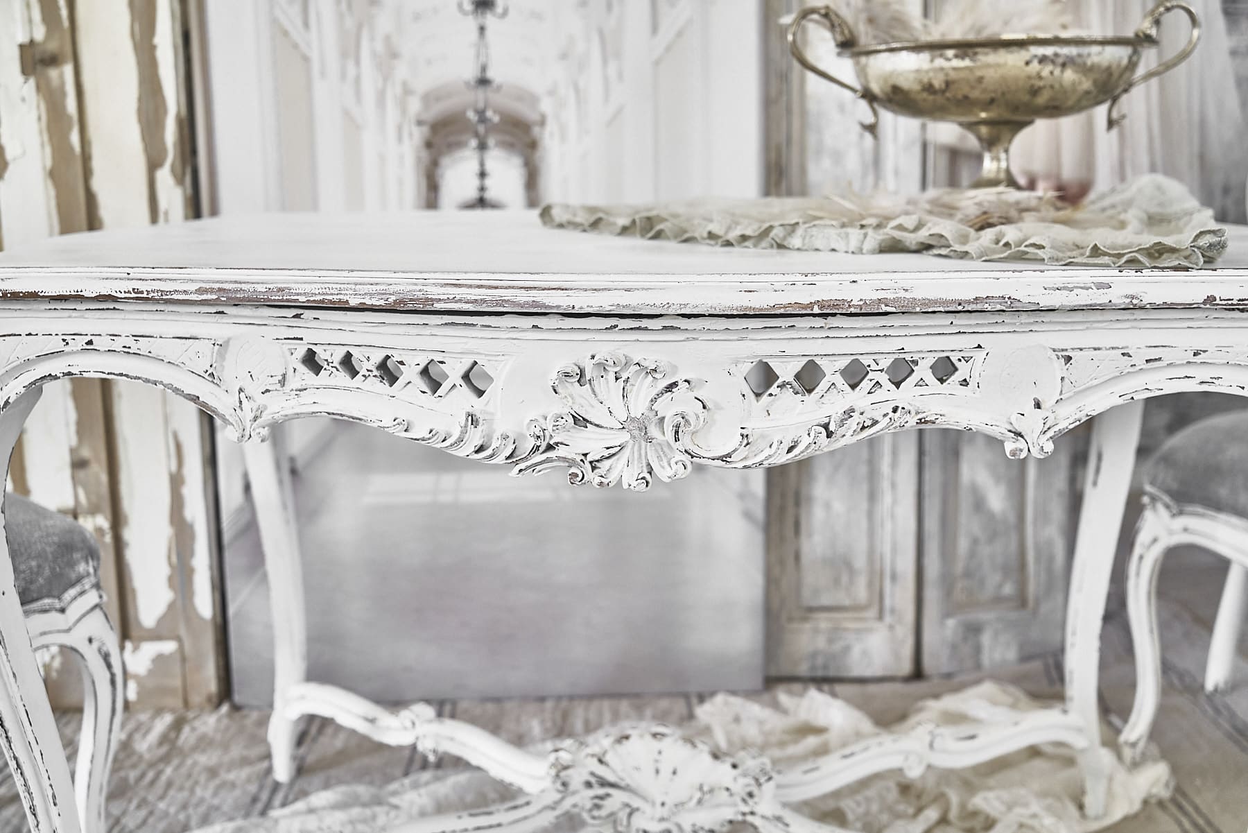 Detailaufnahme eines eleganten antiken Tisches mit Verzierungen und weißer Lackierung